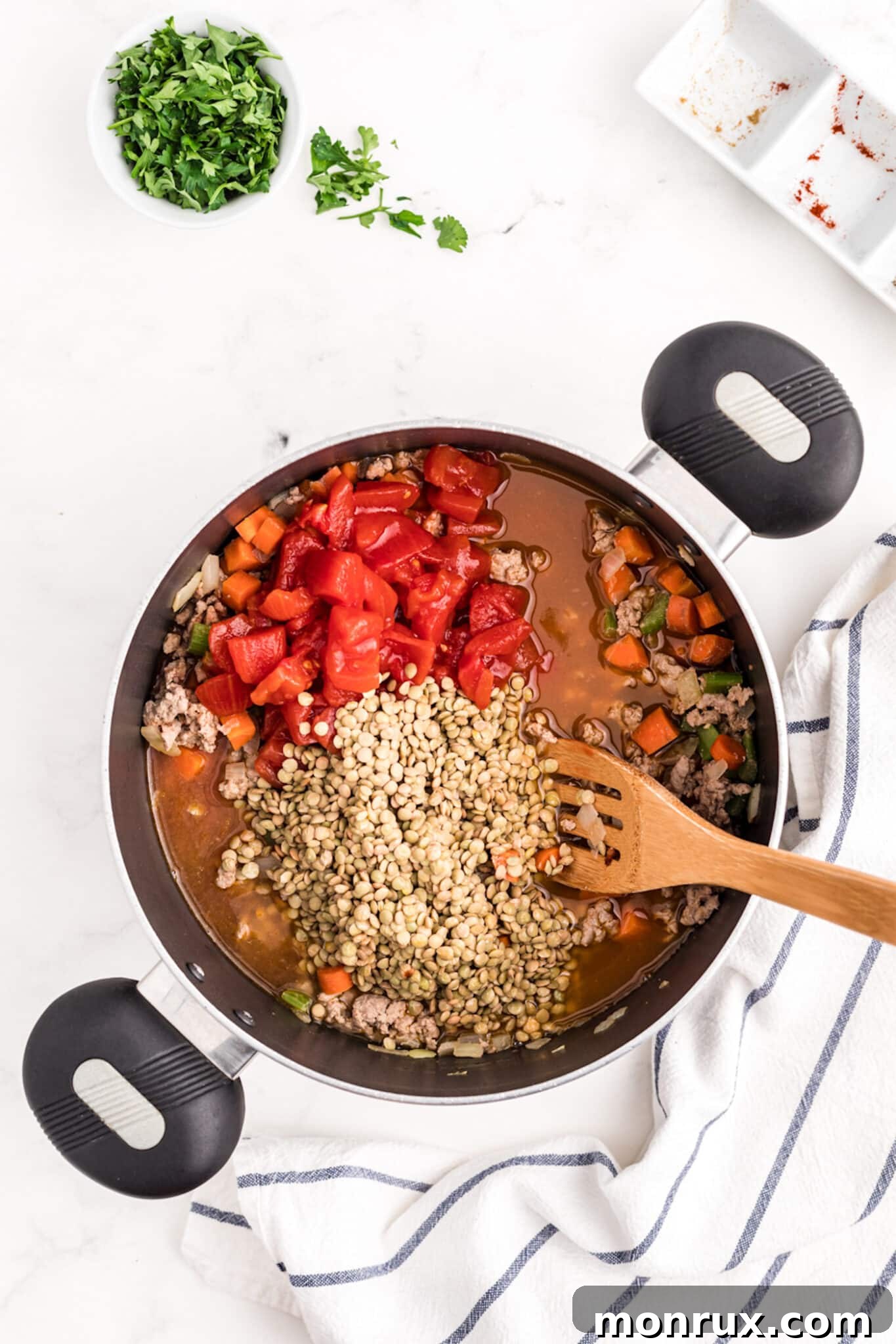Ground turkey, thoroughly rinsed lentils, and a can of diced tomatoes being added to the pot with sautéed vegetables.