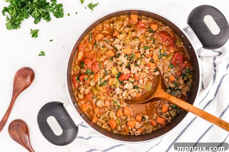 A pot of delicious, steaming ground turkey lentil soup ready to be served.