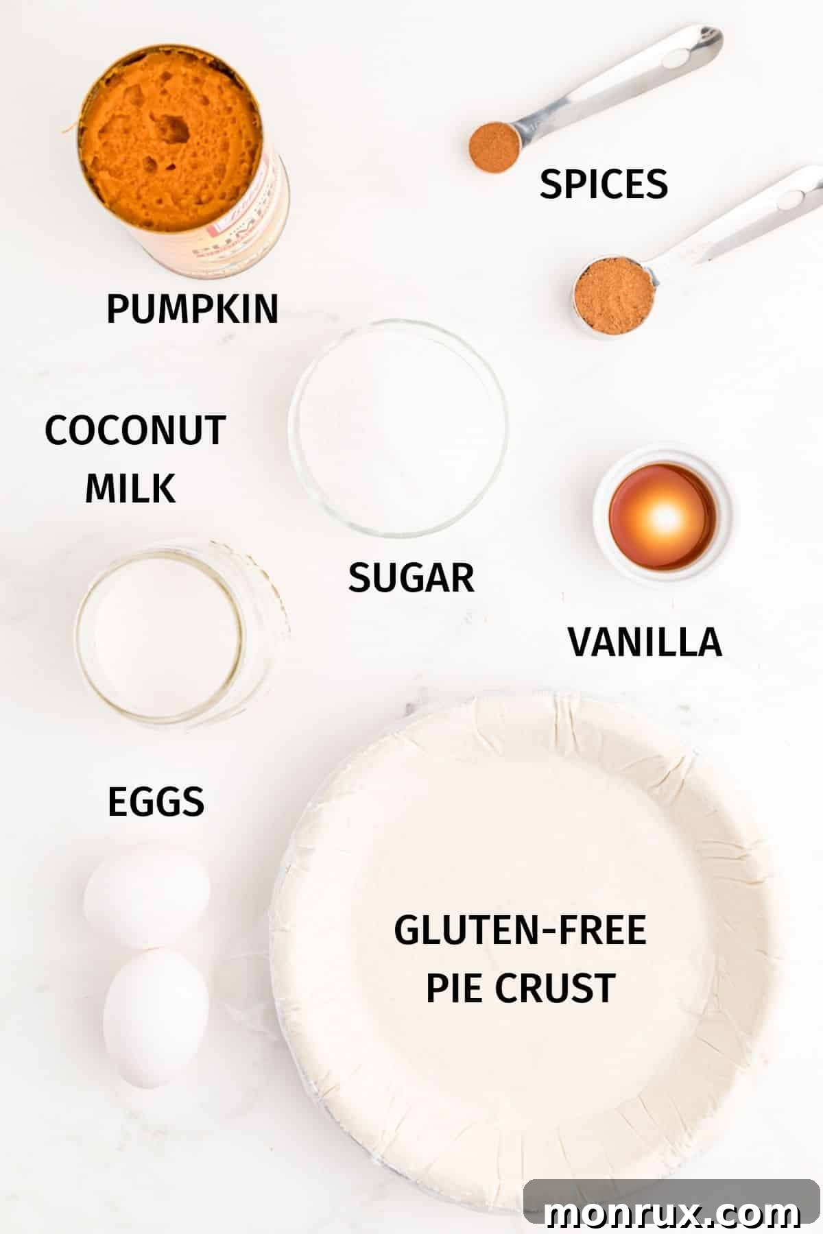 A vibrant flat lay photo displaying all the key ingredients needed for the dairy-free pumpkin pie filling, including a can of pumpkin puree, a can of coconut milk, eggs, sugar, and various spices.
