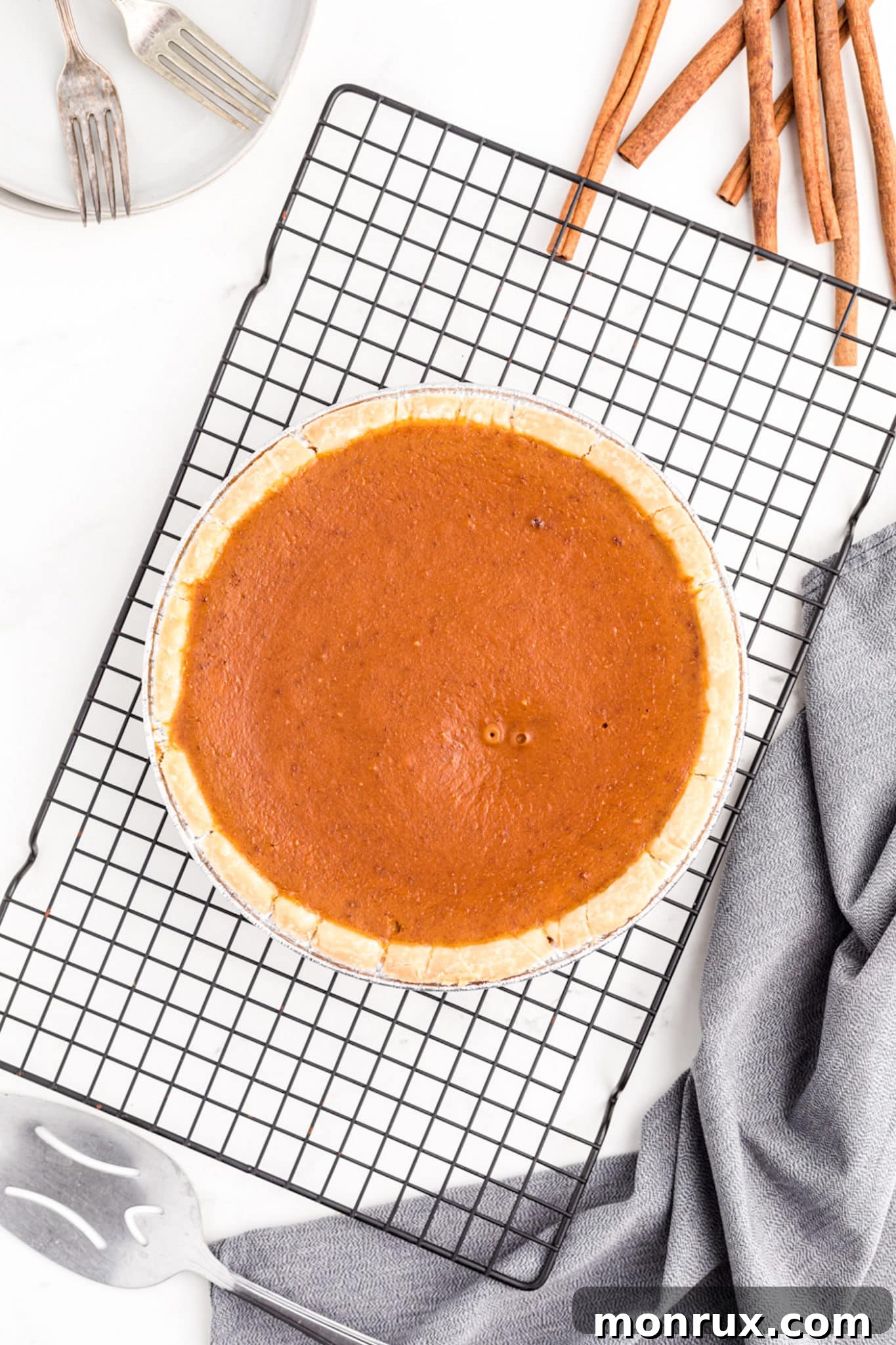 A freshly baked gluten-free and dairy-free pumpkin pie cooling on a wire rack, its golden-brown crust and smooth filling hinting at its deliciousness.