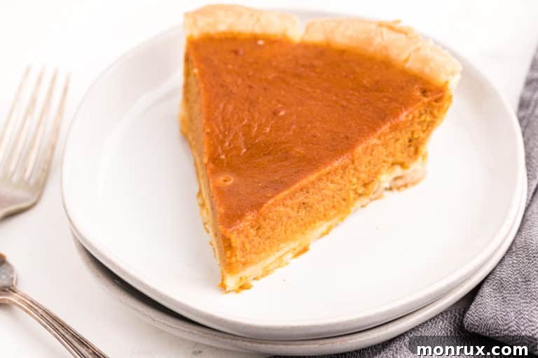 A delicious slice of gluten-free, dairy-free pumpkin pie served on a white plate with a side of coconut whipped cream, ready to be eaten.