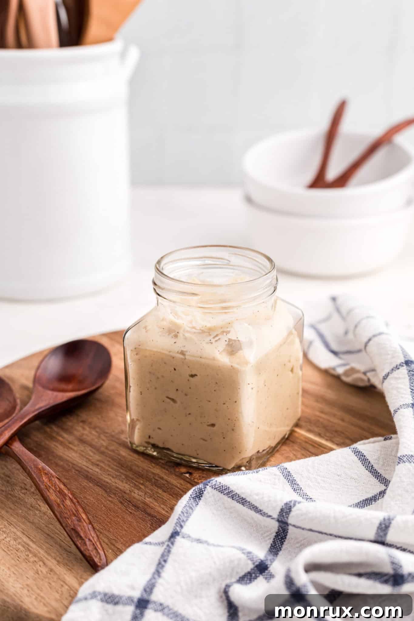 A glass jar of homemade gluten-free dairy-free cream of chicken soup sitting on a kitchen countertop.