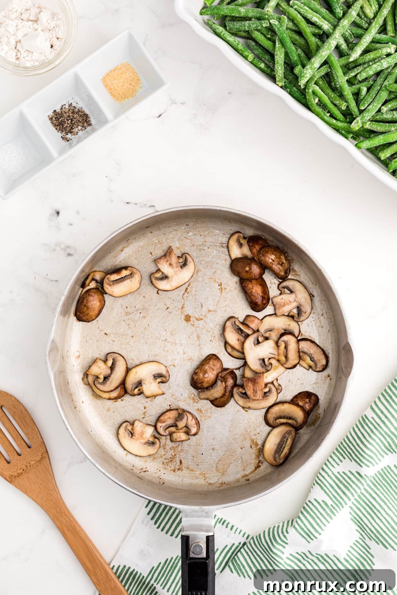 Slicing fresh mushrooms in a skillet, cooking them until tender and lightly browned for the dairy-free green bean casserole sauce.