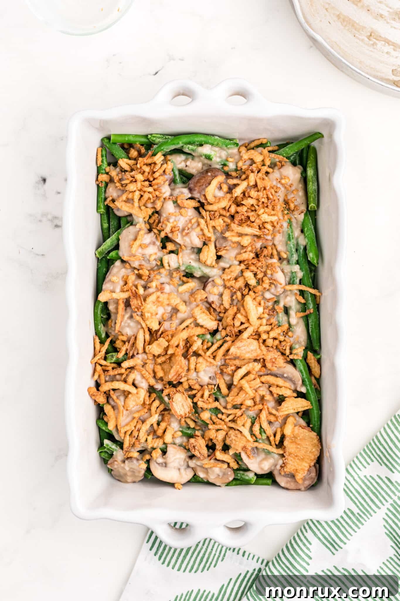 The assembled dairy-free green bean casserole, topped generously with crispy fried onions, ready to be baked to golden perfection.