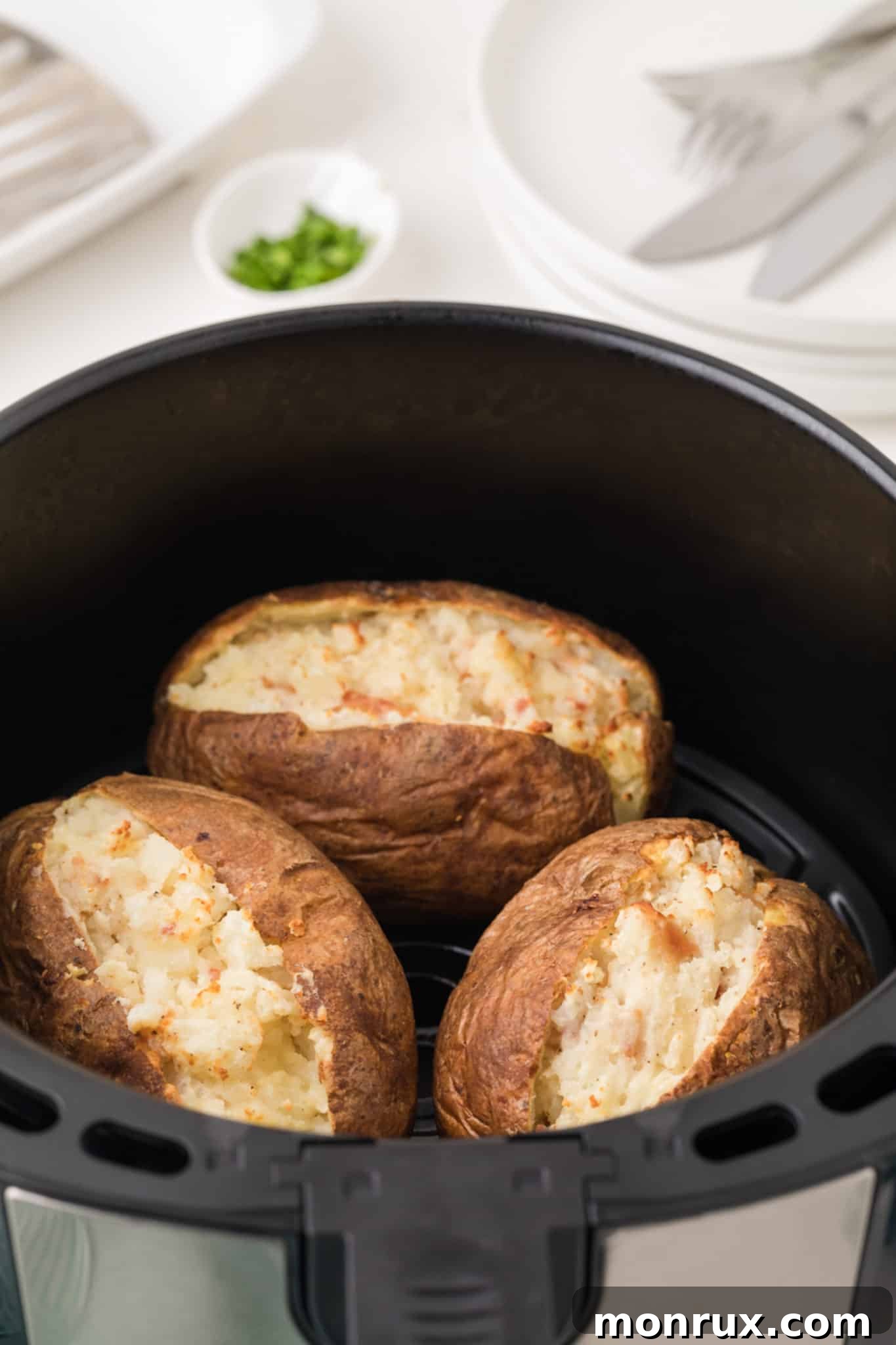 Two halves of air fryer twice baked potatoes, golden brown and perfectly cooked, nestled inside the basket of an air fryer, steam gently rising.
