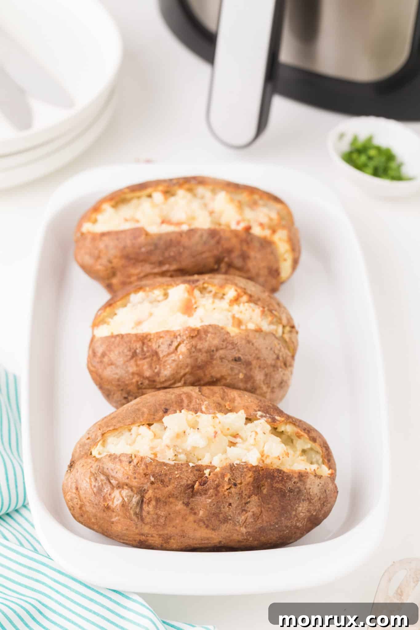 A serving tray filled with several golden brown air fryer twice baked potatoes, garnished with fresh green herbs, ready to be served at a gathering.