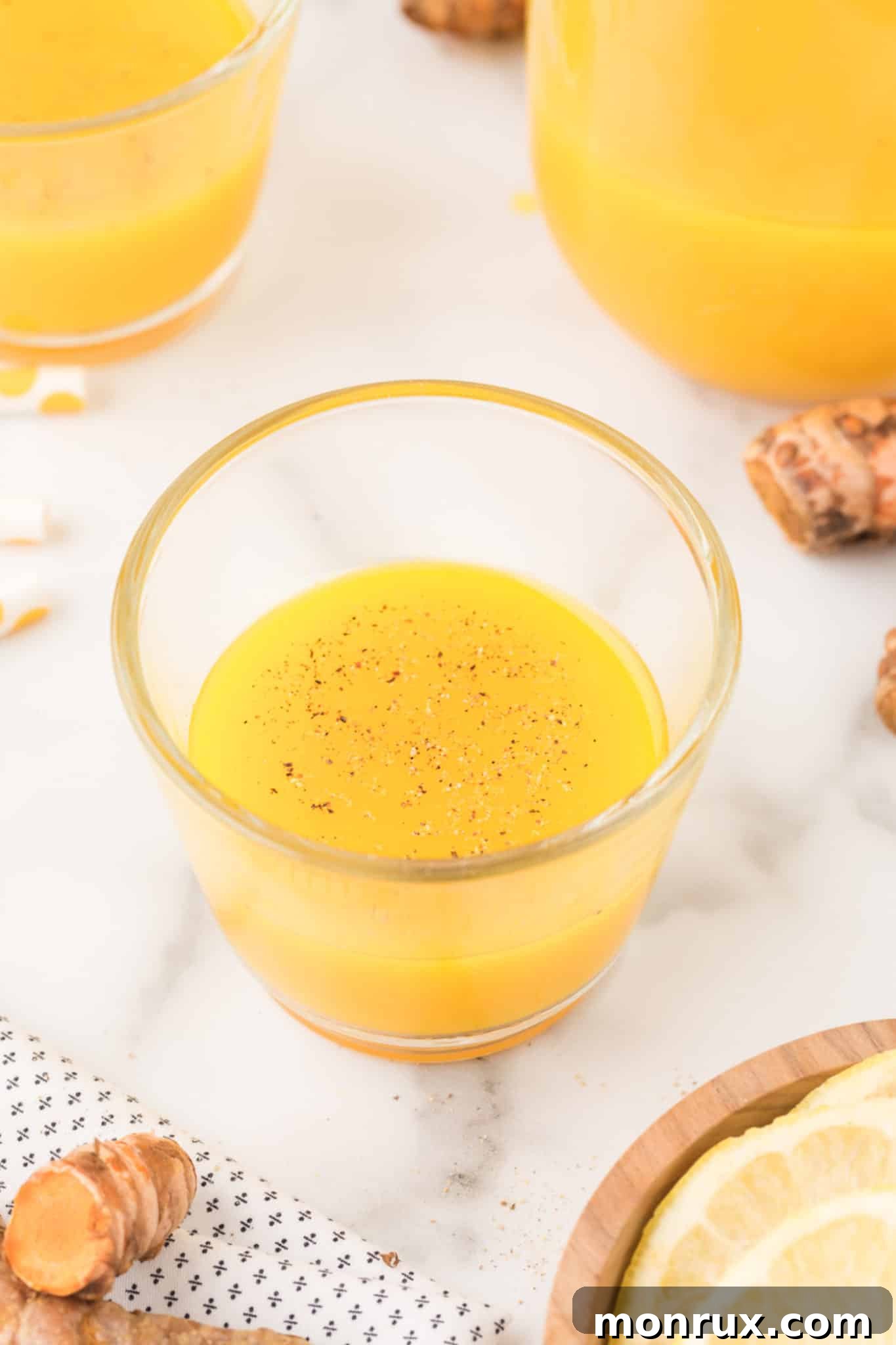turmeric shot in a glass with ground black pepper on top.