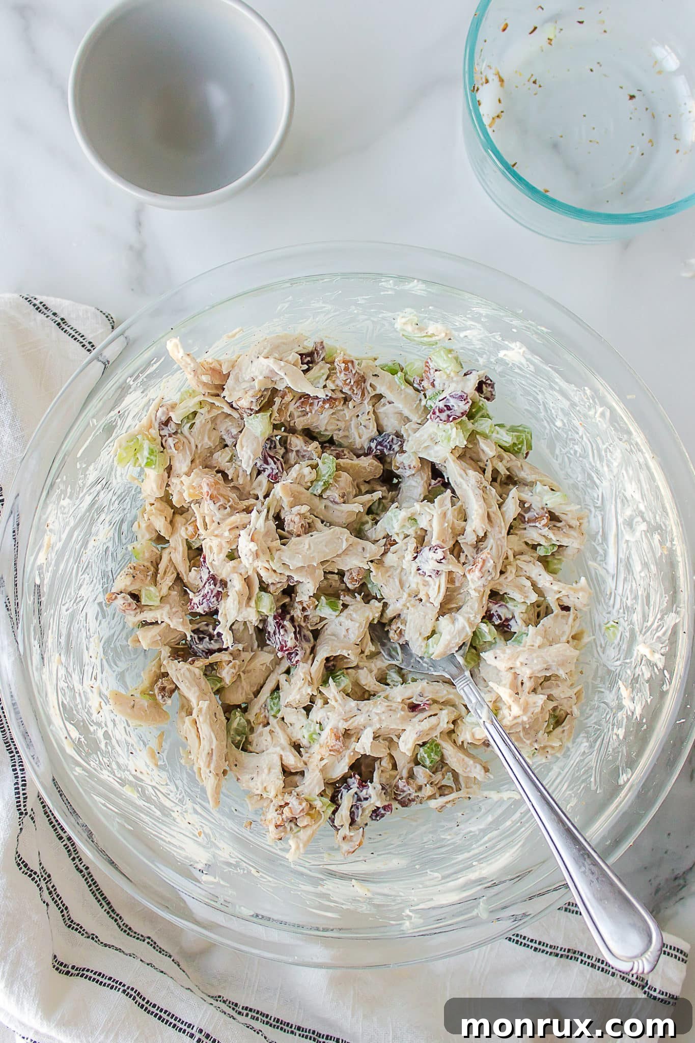 A large mixing bowl filled with freshly prepared shredded chicken salad, ready to be chilled or served.