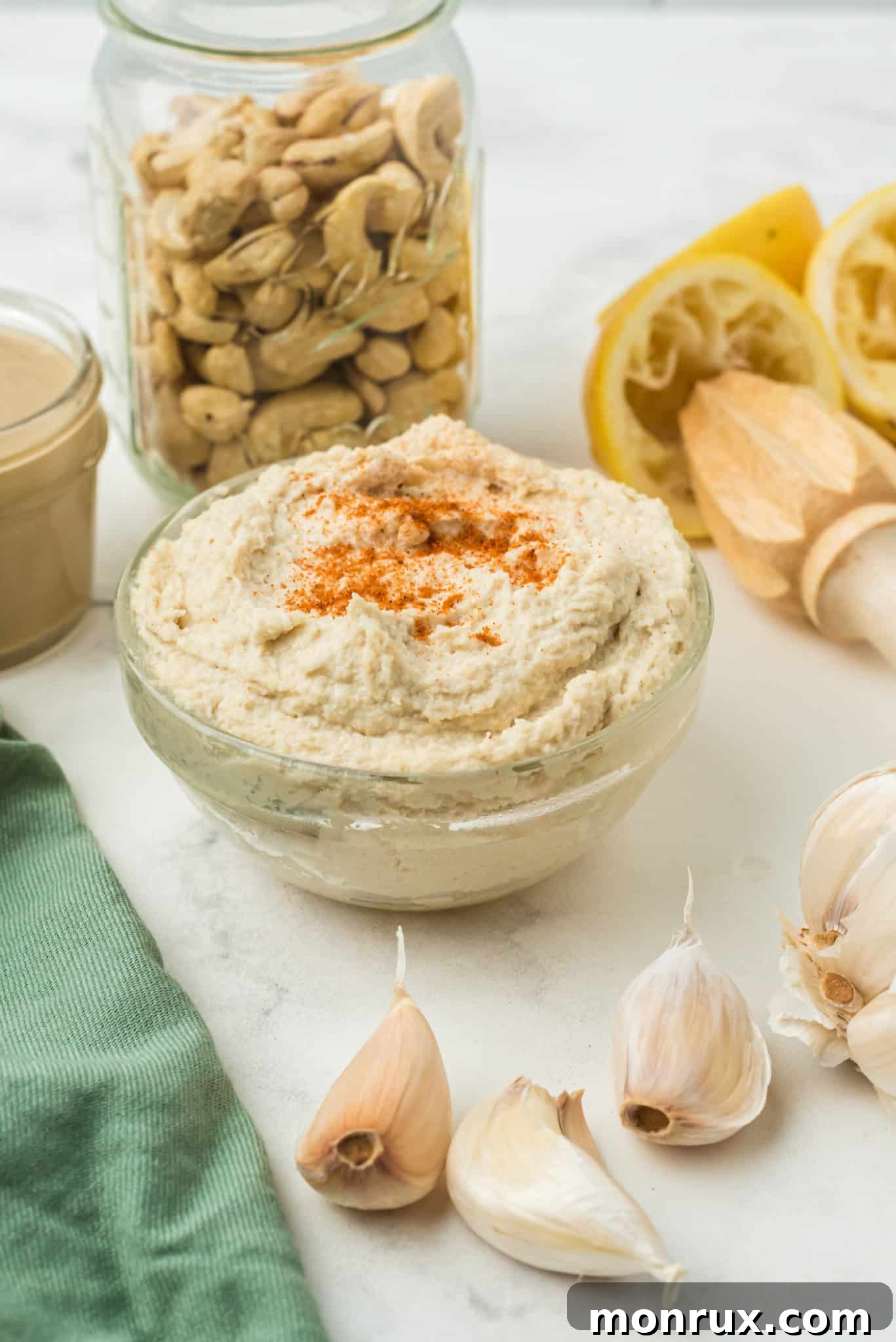 A beautifully presented bowl of creamy cashew hummus, garnished with a sprinkle of paprika and a drizzle of olive oil, ready to be enjoyed.