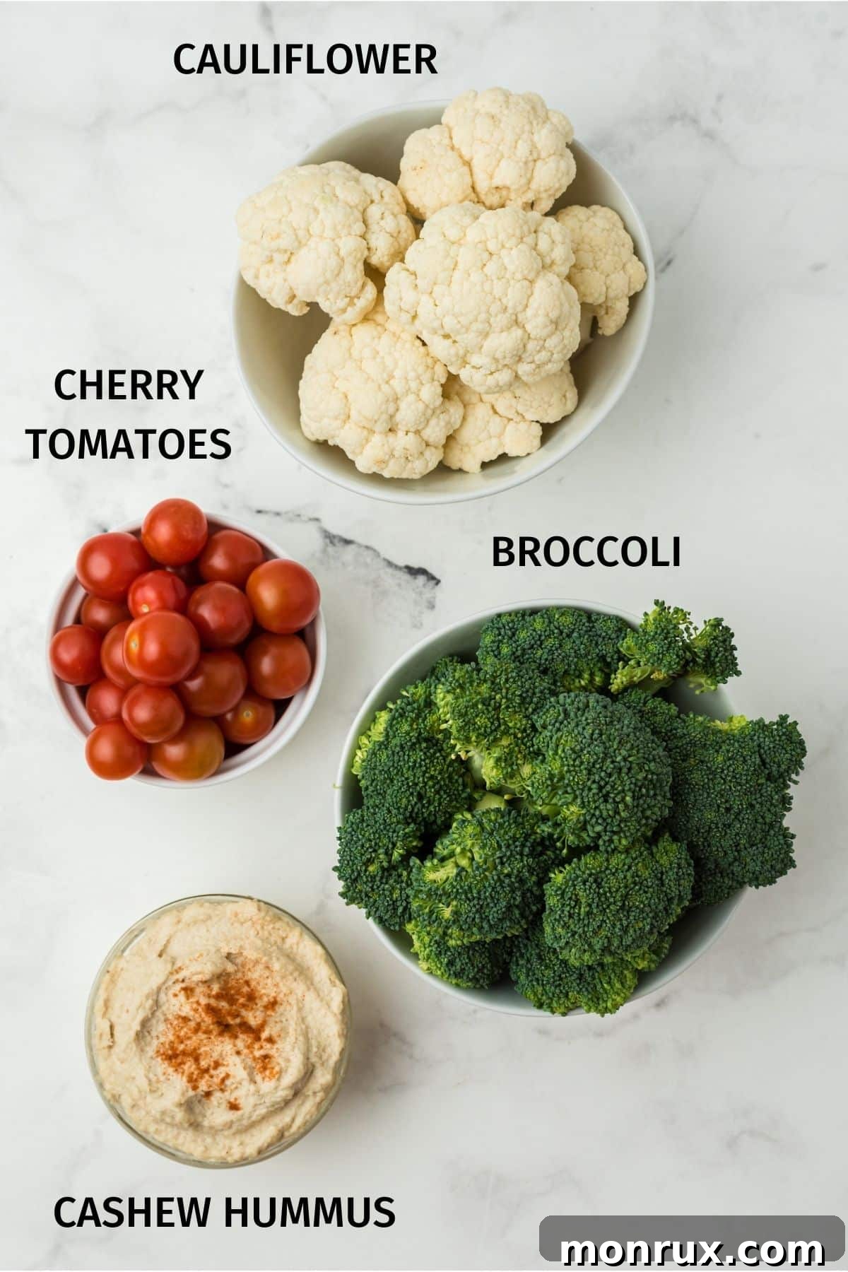 Ingredients laid out for a vegetable holiday wreath, featuring fresh broccoli, cauliflower, cherry tomatoes, and a bowl of dip.