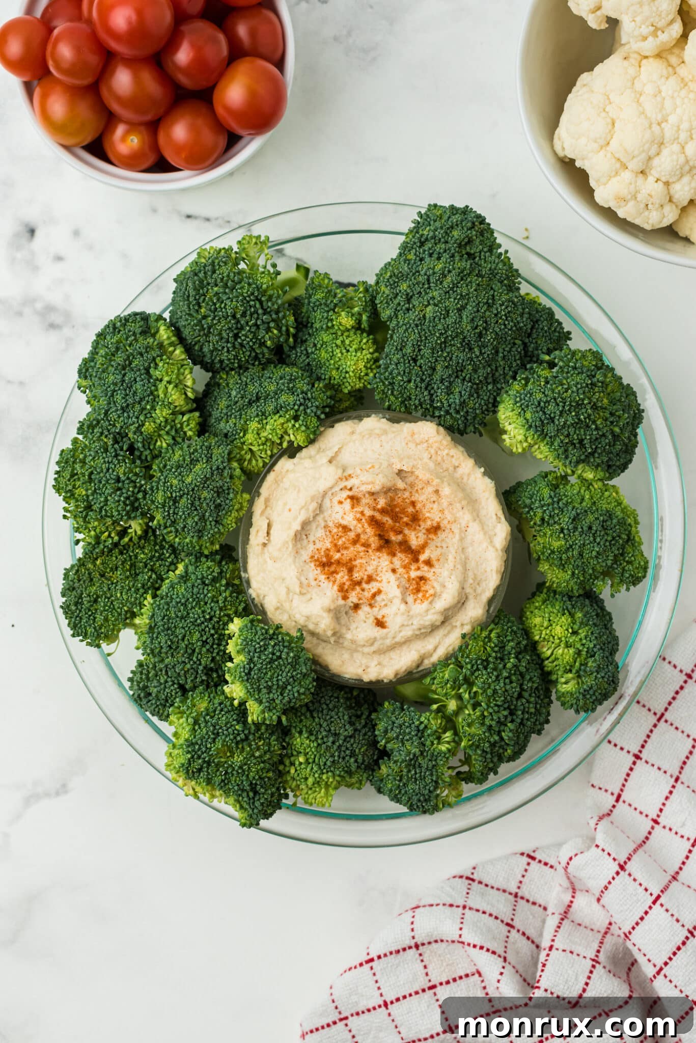 Fresh broccoli florets arranged around the central dip bowl, forming the green base of the Christmas veggie wreath.