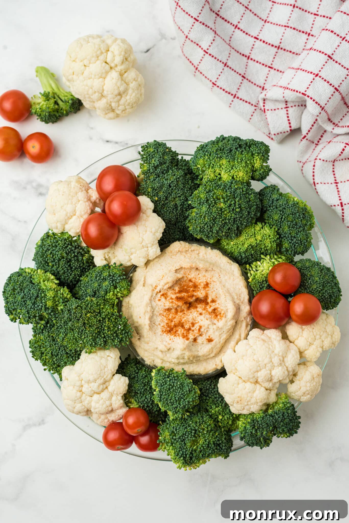 The finished holiday veggie wreath decorated with cauliflower florets and cherry tomatoes, resembling ornaments and berries.