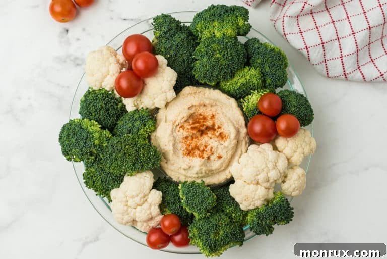 A beautifully arranged holiday vegetable wreath, garnished with fresh herbs and a central dip, ready for serving.