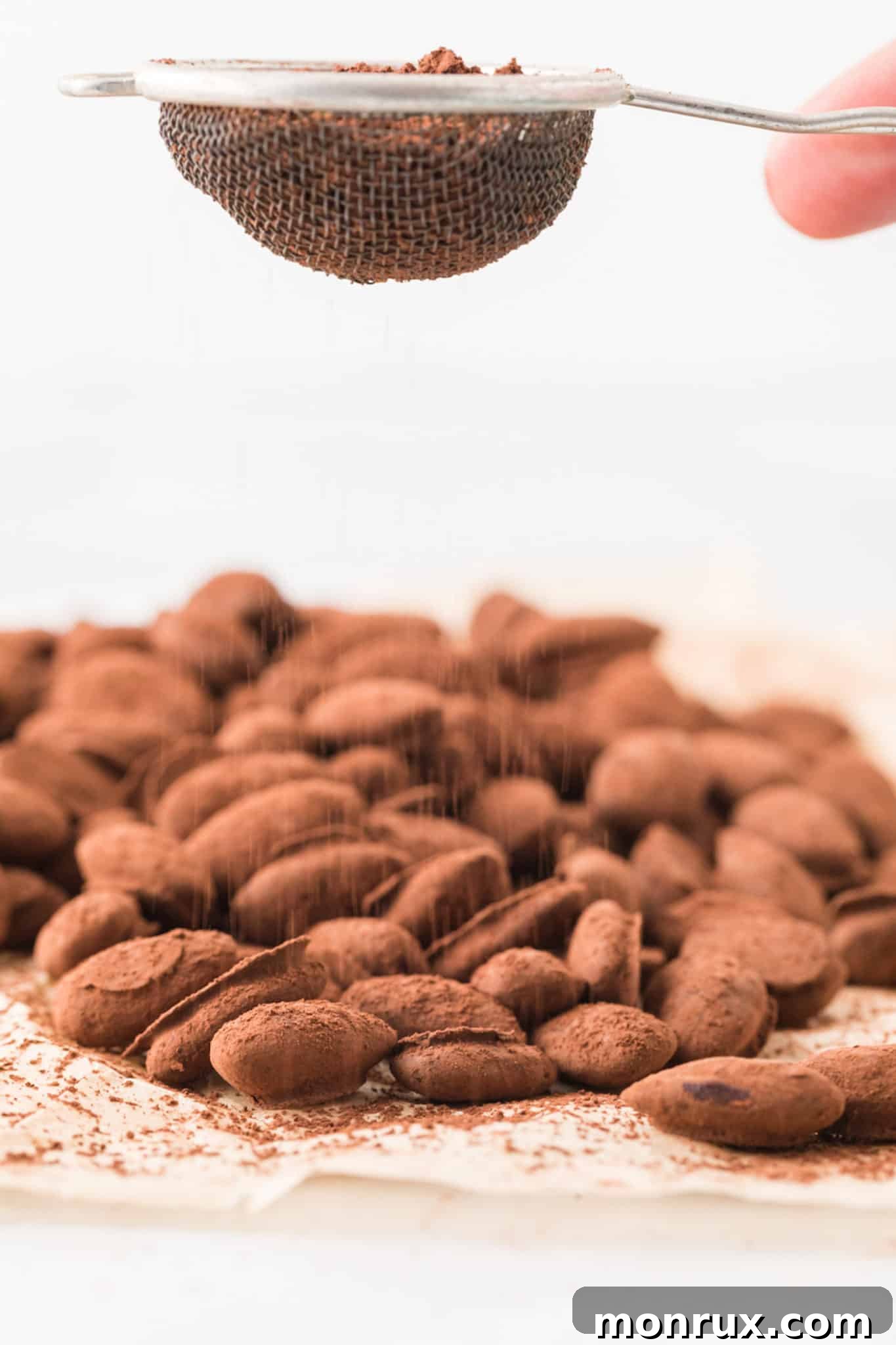 sifting cocoa powder onto almonds.