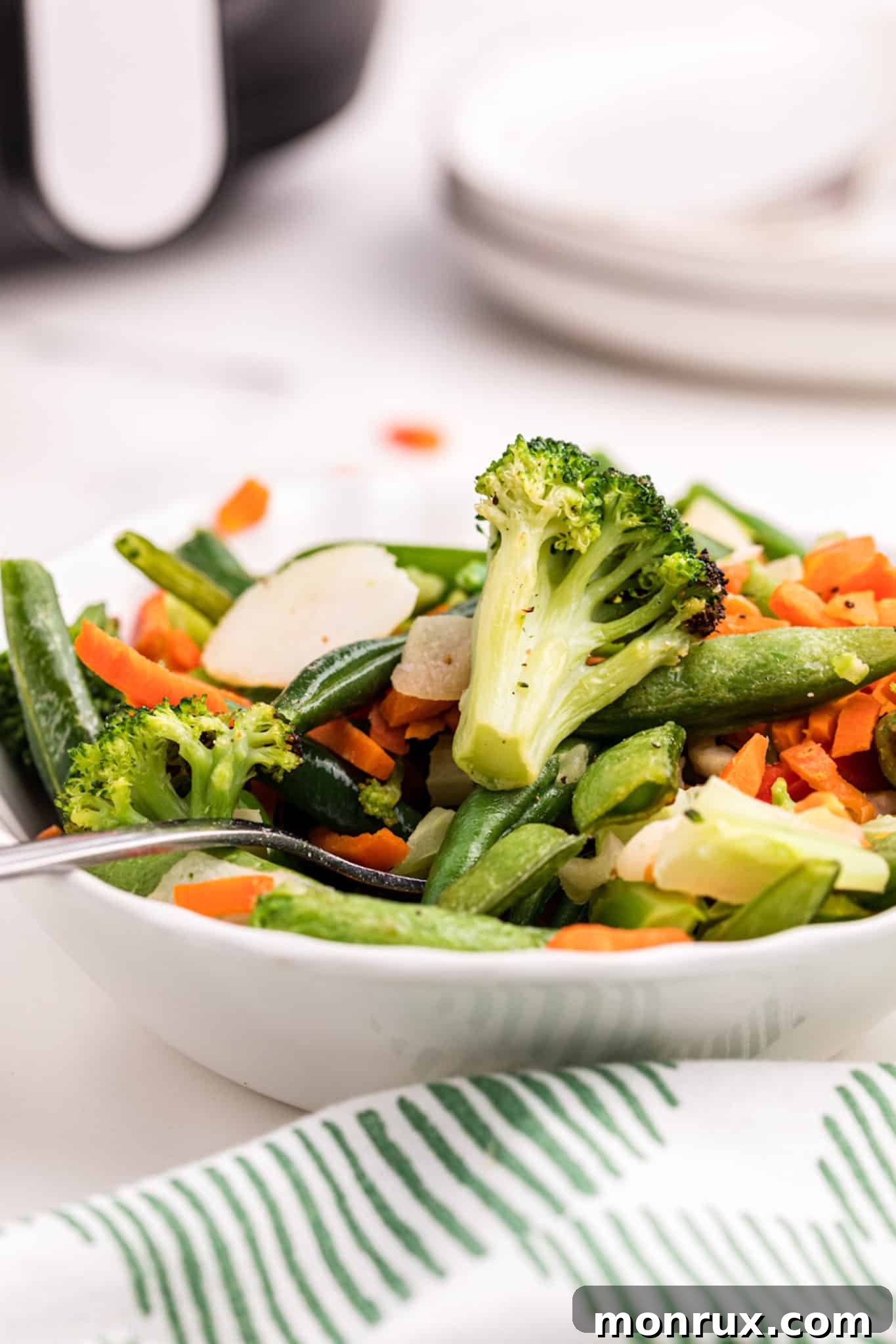 A vibrant bowl of cooked air-fried stir-fry vegetables, showcasing their crispy texture.
