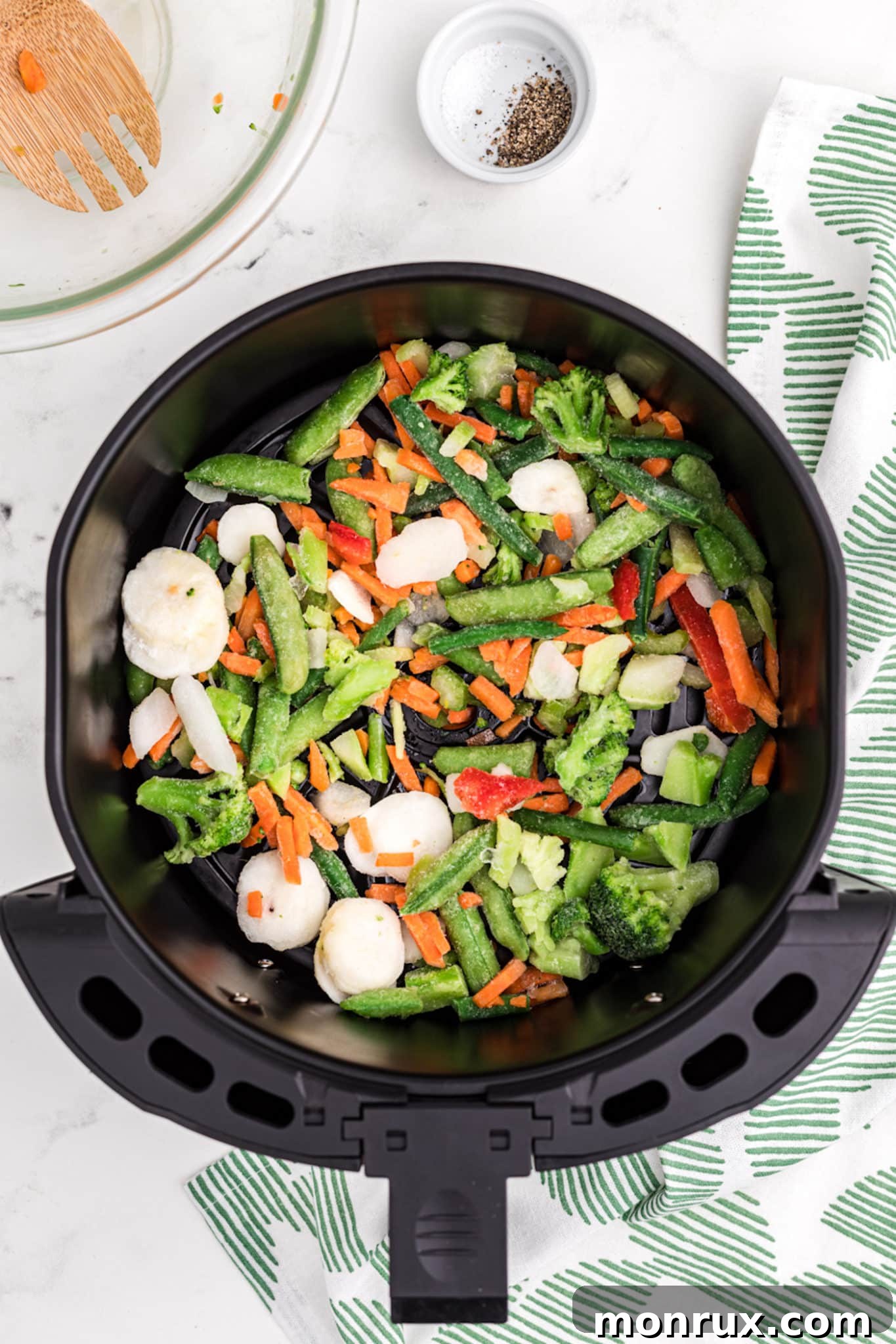 Frozen vegetables placed inside an air fryer basket, ready for cooking.