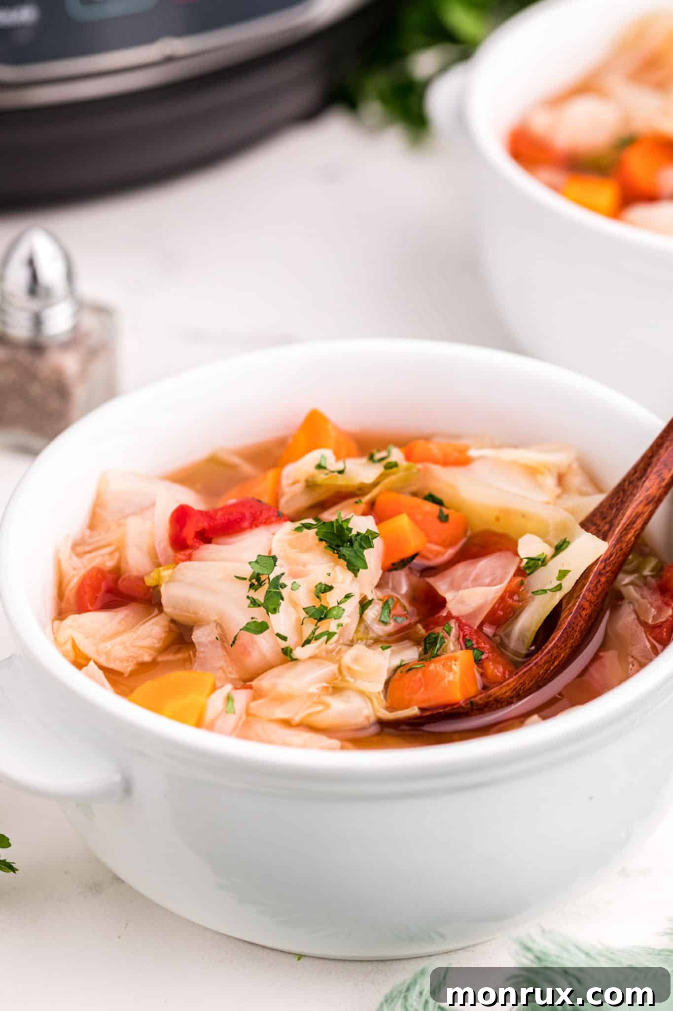 A steaming bowl of vibrant detox cabbage soup, garnished with fresh herbs.