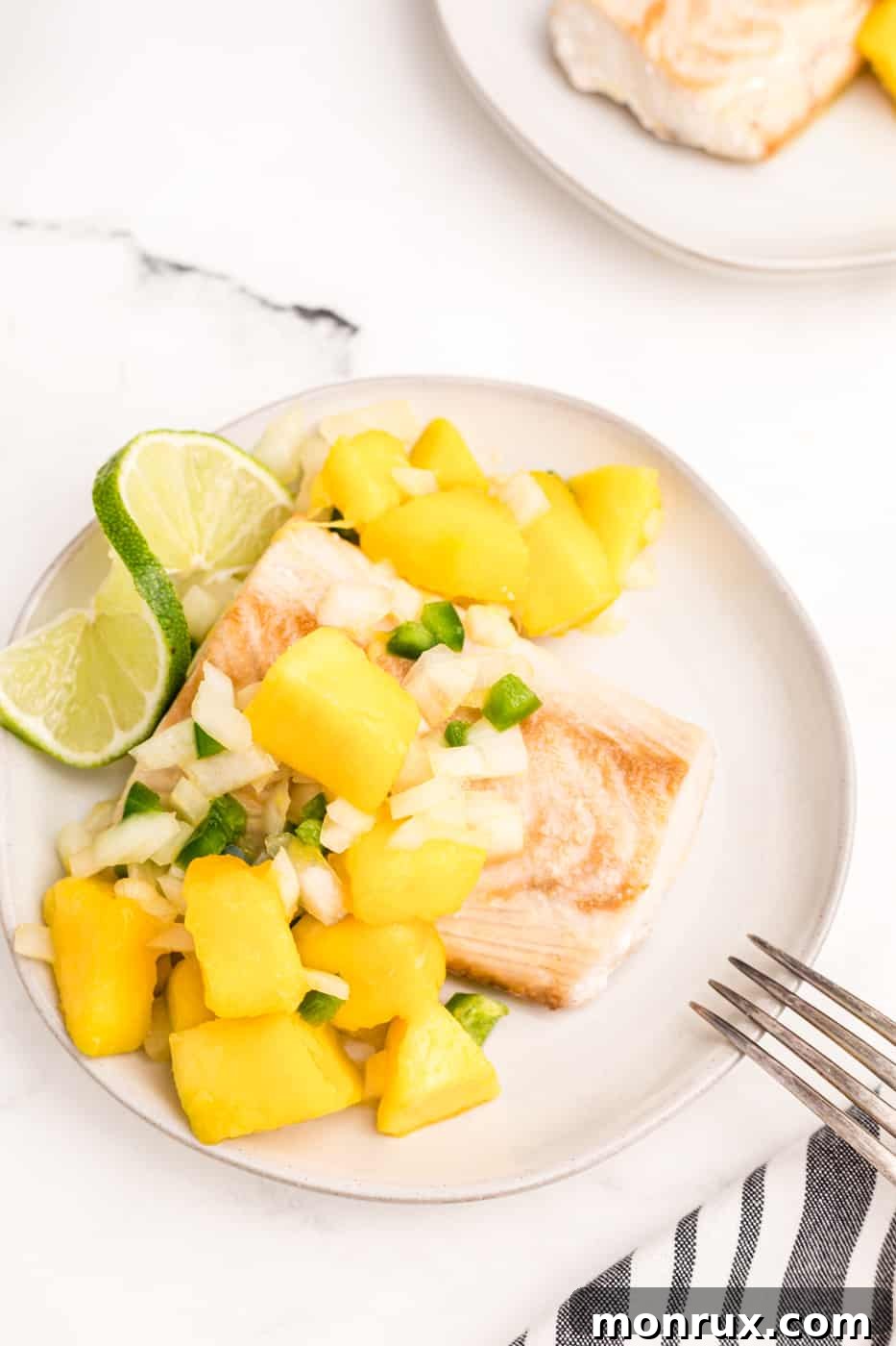 air fried mahi mahi with mango salsa on white plate, garnished with fresh cilantro.
