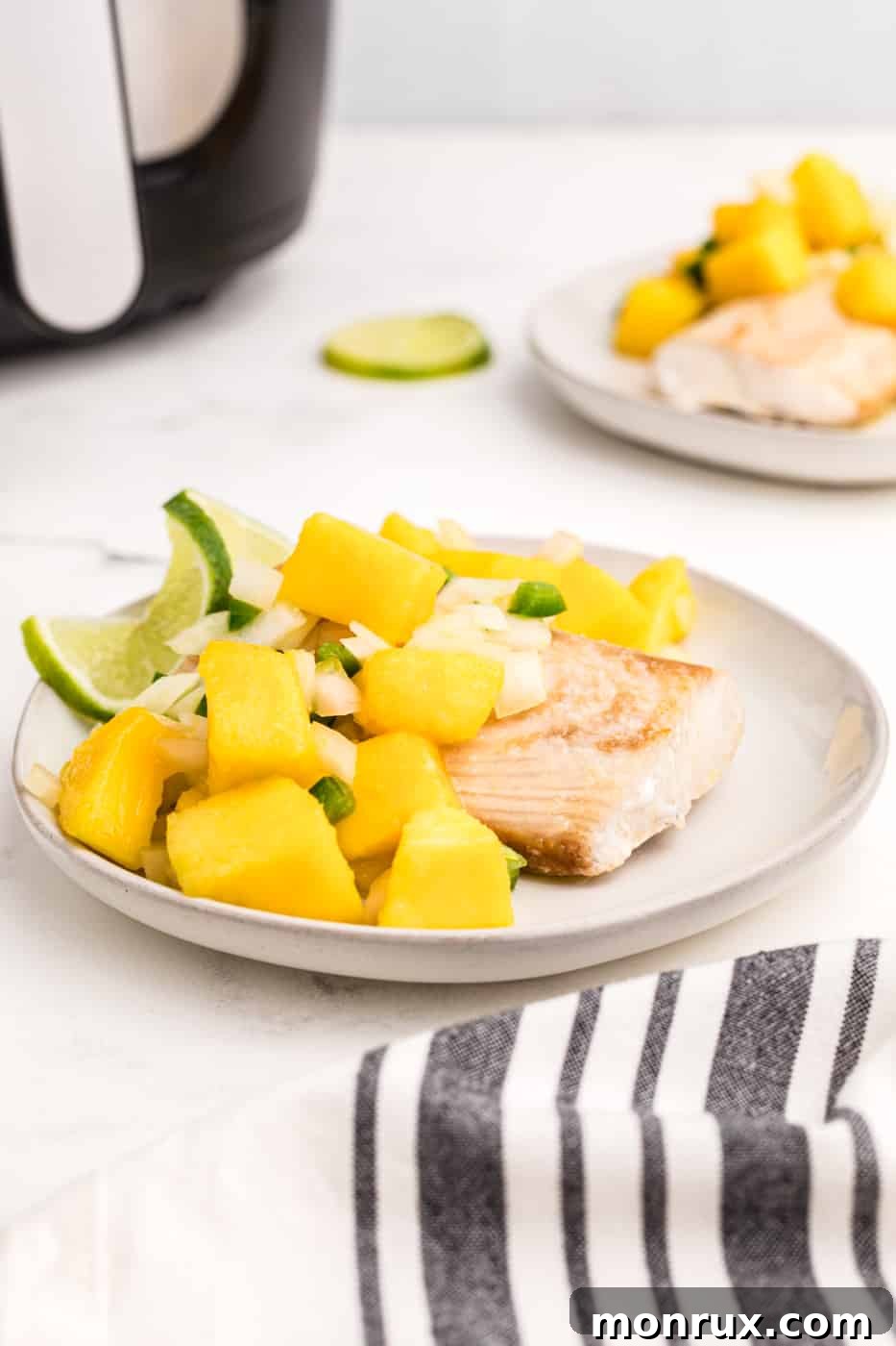 a plate of air fried mahi mahi with mango salsa, garnished with fresh herbs.
