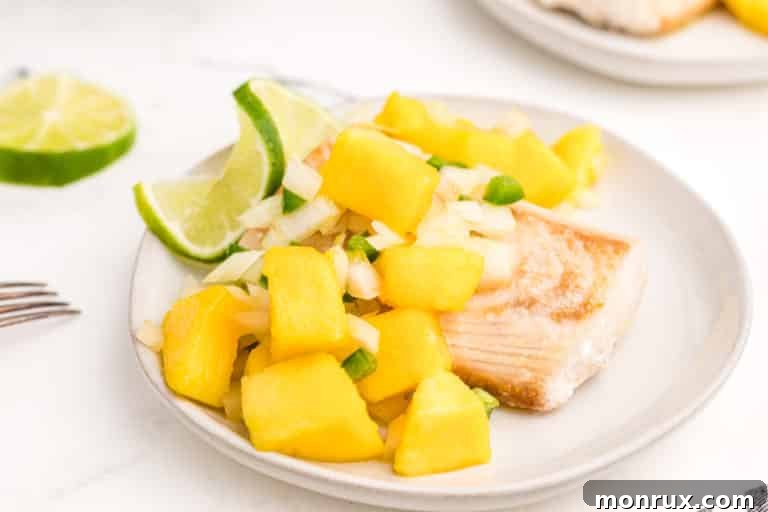 air fryer mahi mahi with salsa on plate, garnished with fresh cilantro and lime wedges.