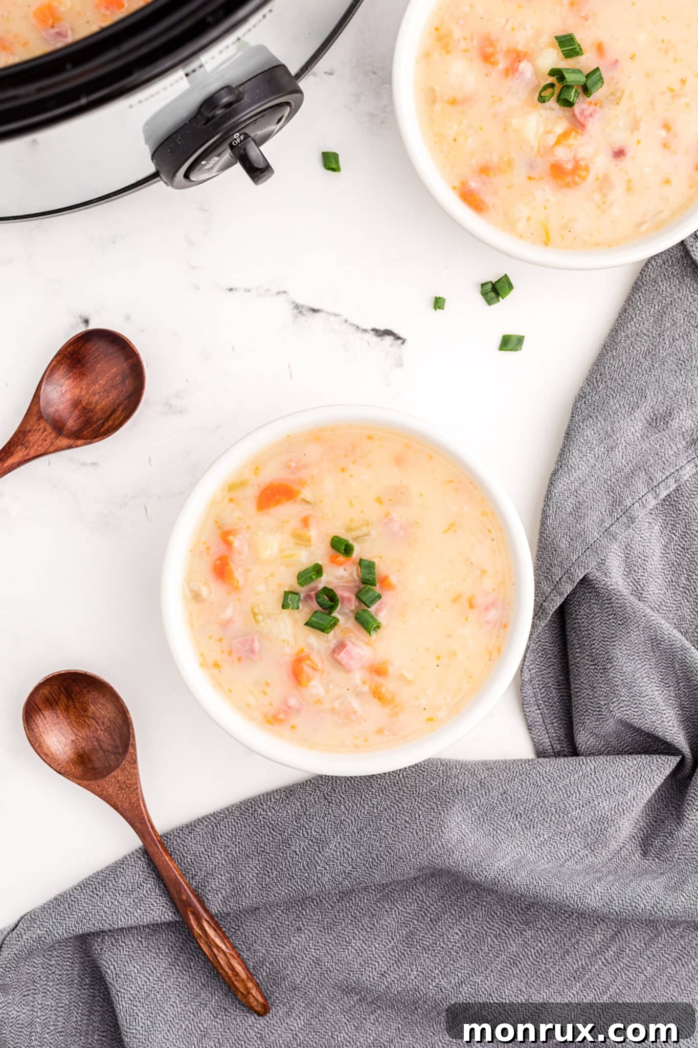 A comforting bowl of creamy slow cooker ham and potato soup, garnished with fresh herbs, perfect for a cold day.