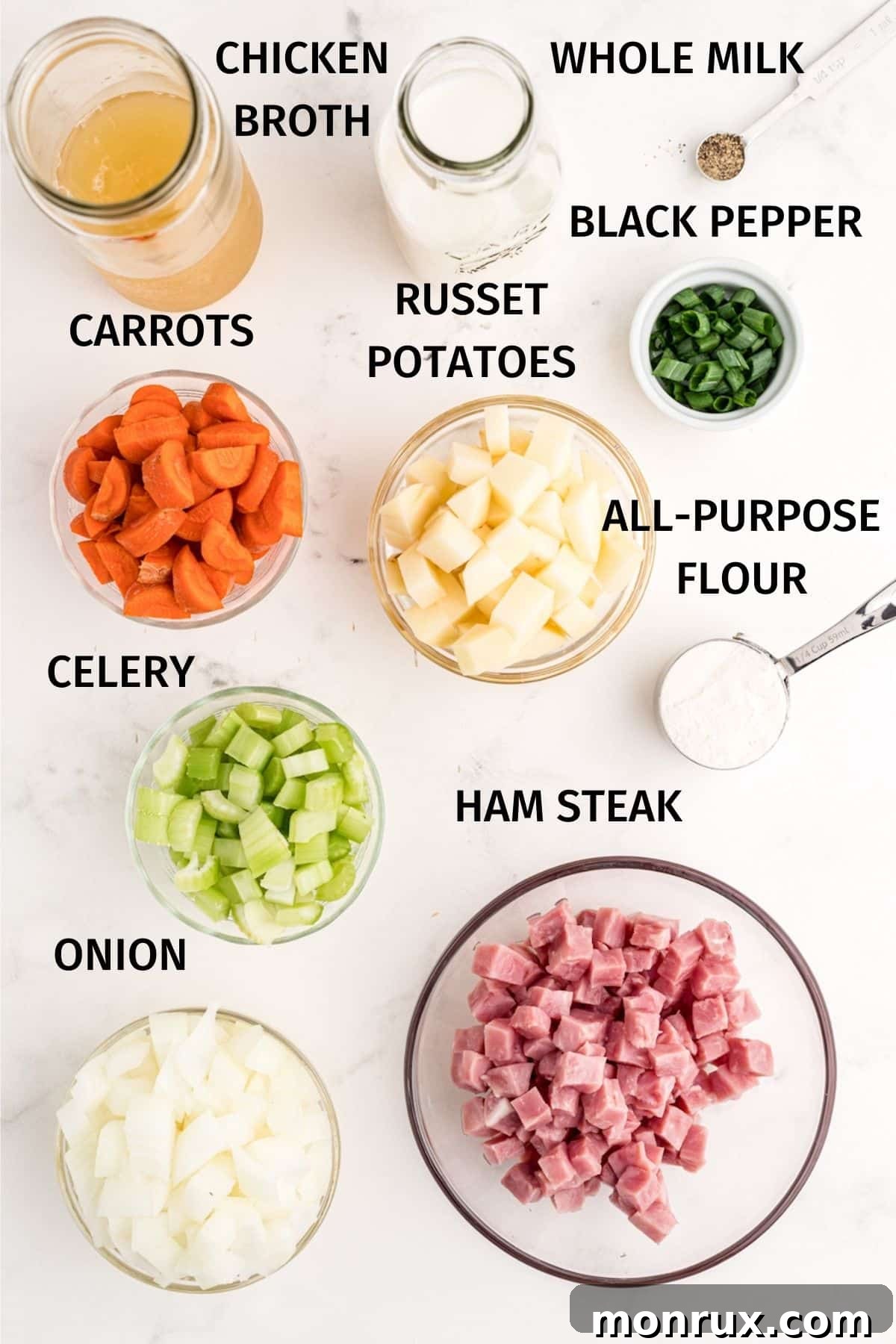 A flat lay image displaying all the fresh ingredients required for crockpot ham and potato soup, including diced ham, potatoes, carrots, celery, onion, broth, and milk.