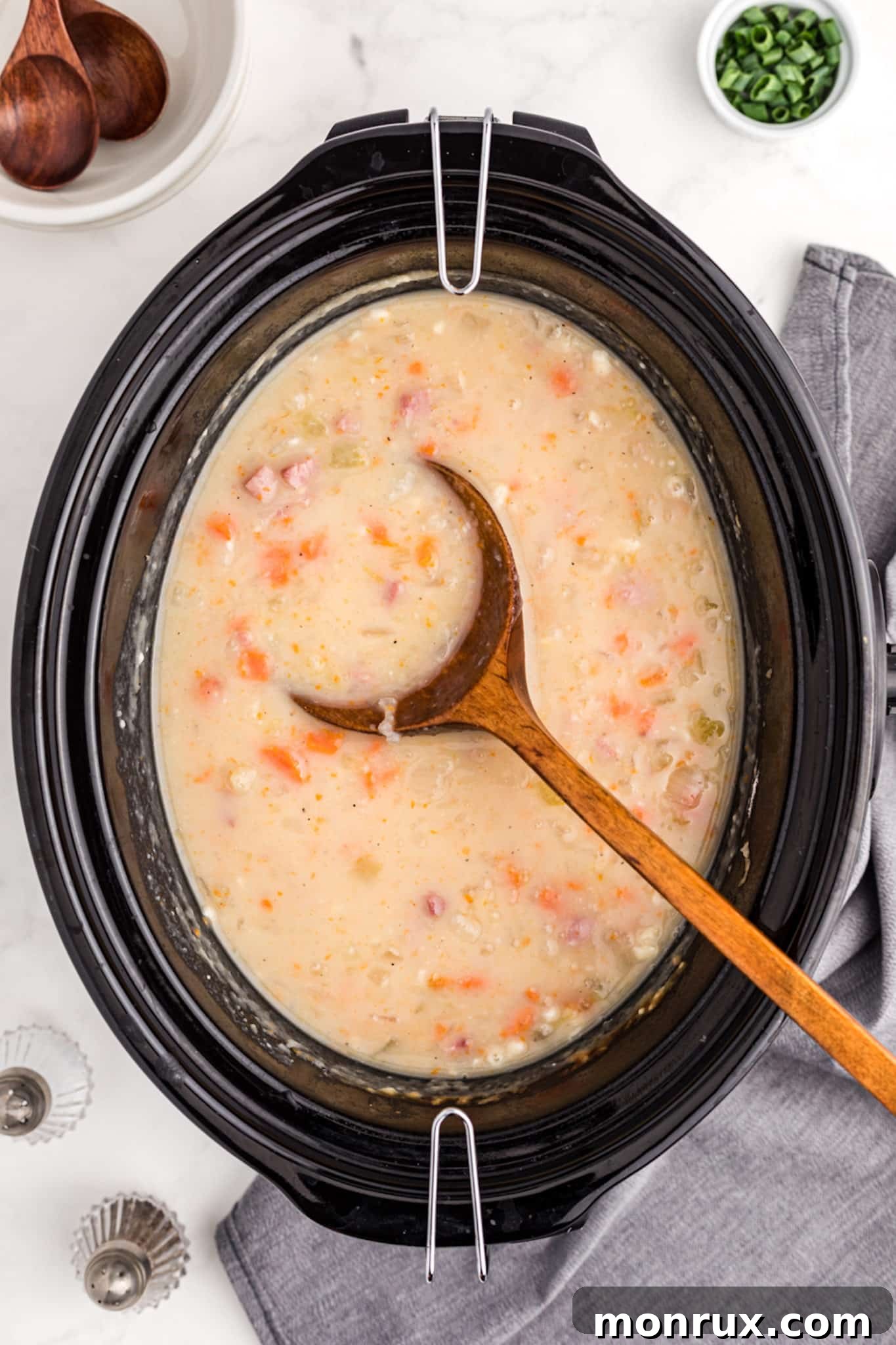 The finished slow cooker ham and potato soup, bubbling gently in the crockpot, ready to be served.