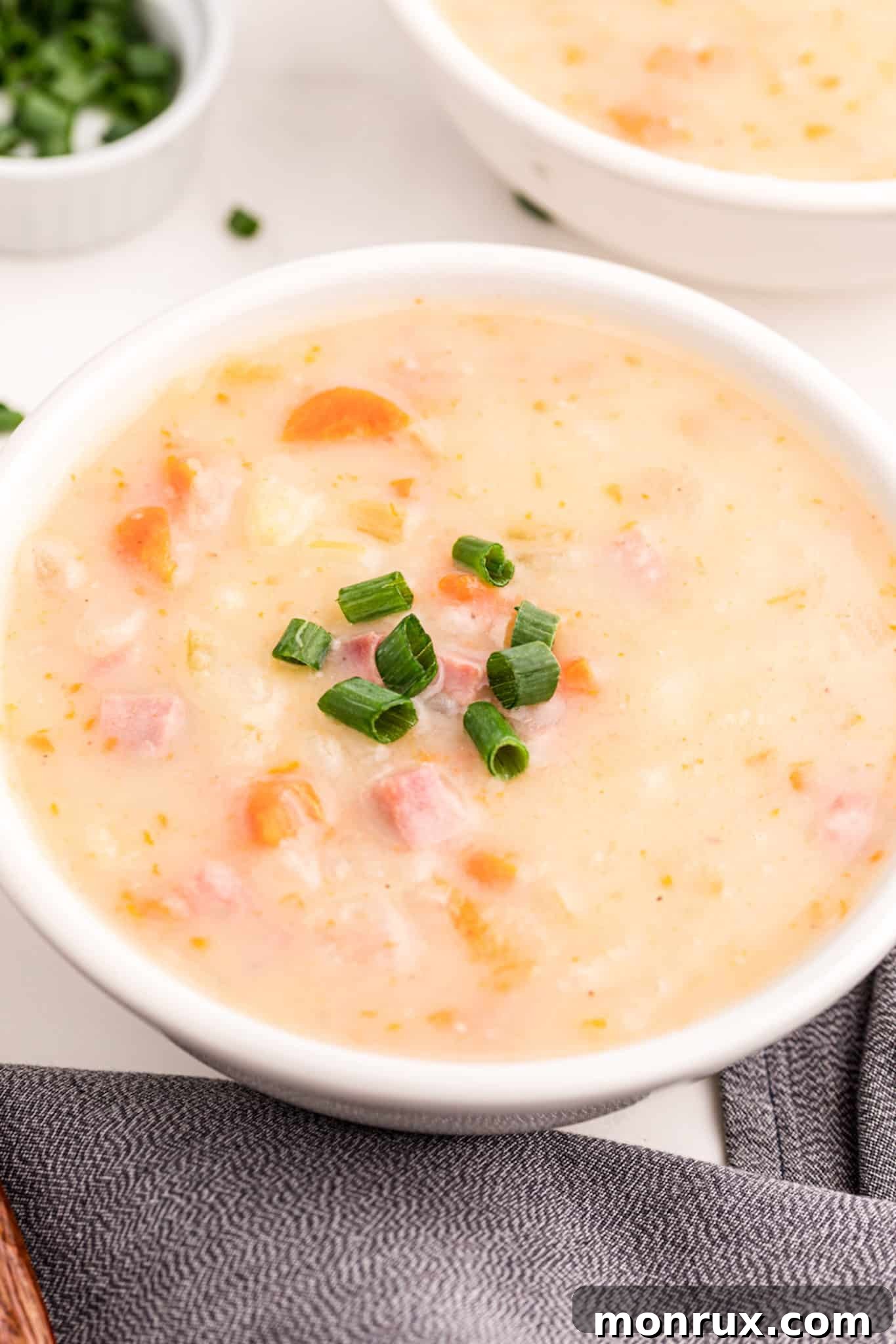A beautifully presented bowl of slow cooker ham and potato soup, garnished with fresh chopped green onions, ready to be enjoyed.