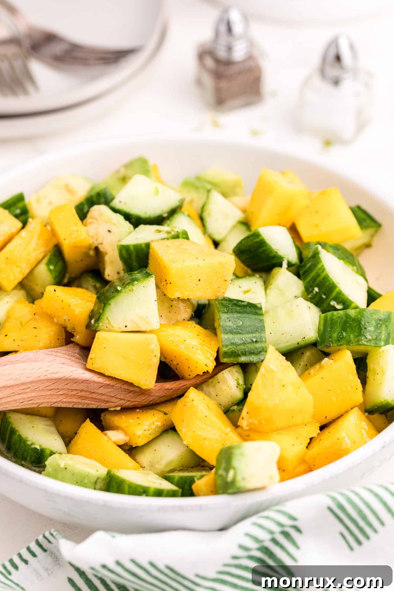A beautifully presented bowl of fresh mango, creamy avocado, and crisp cucumbers, ready to be tossed in a zesty lime dressing.