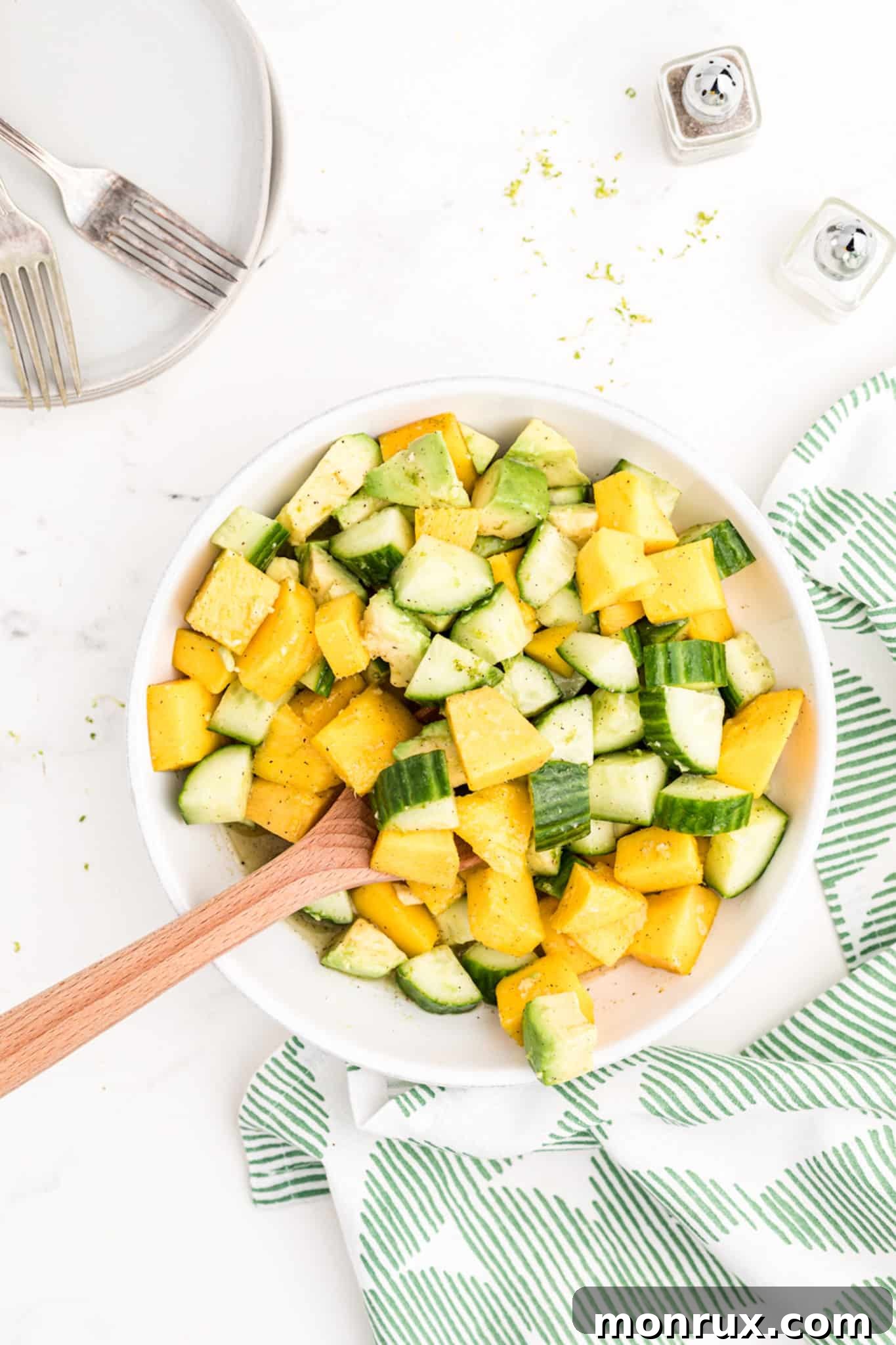 A generous bowl of freshly prepared mango avocado cucumber salad, garnished and ready to be enjoyed.