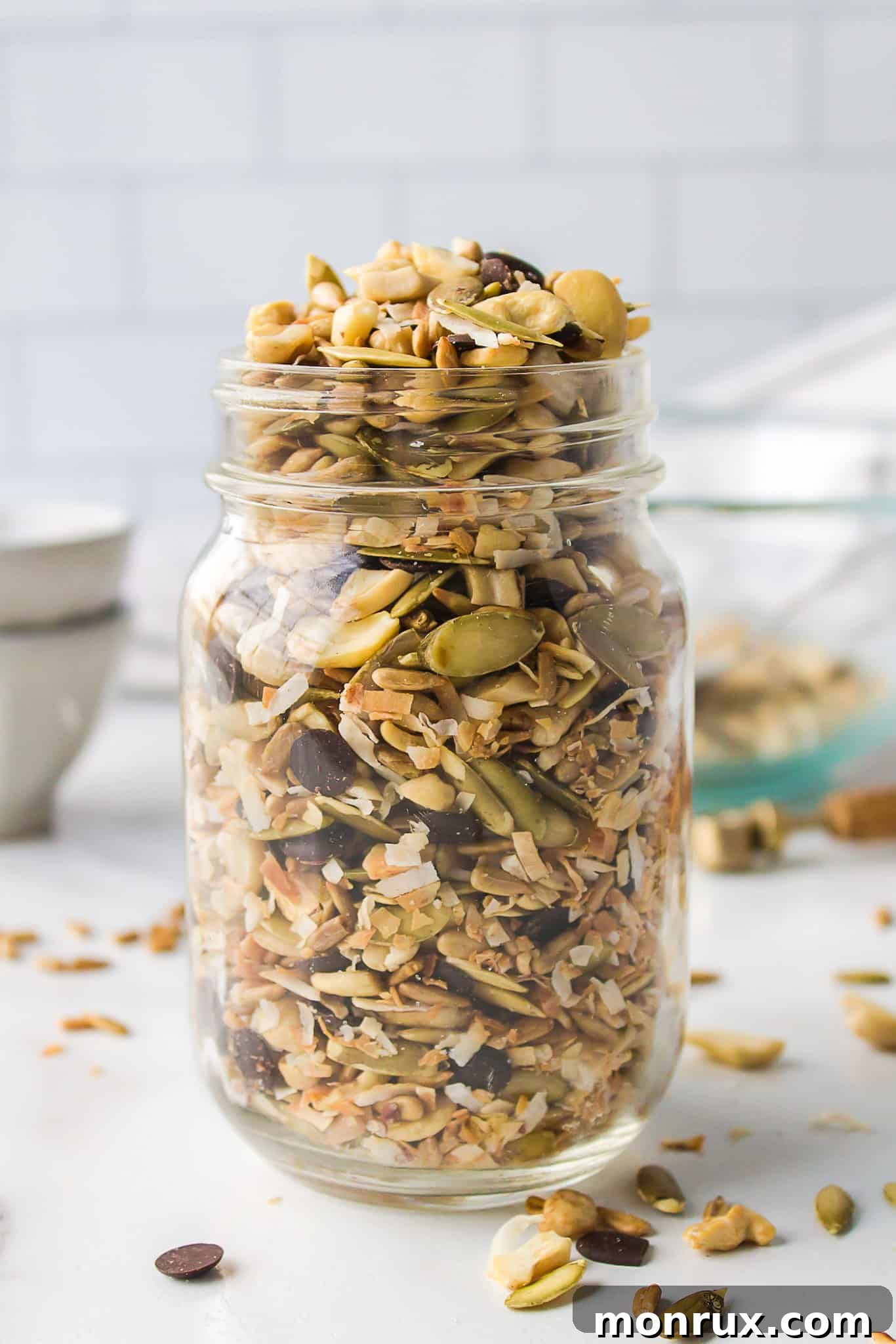 A beautifully arranged jar of homemade sugar-free trail mix, showcasing a vibrant mix of nuts, seeds, and dark chocolate chips.