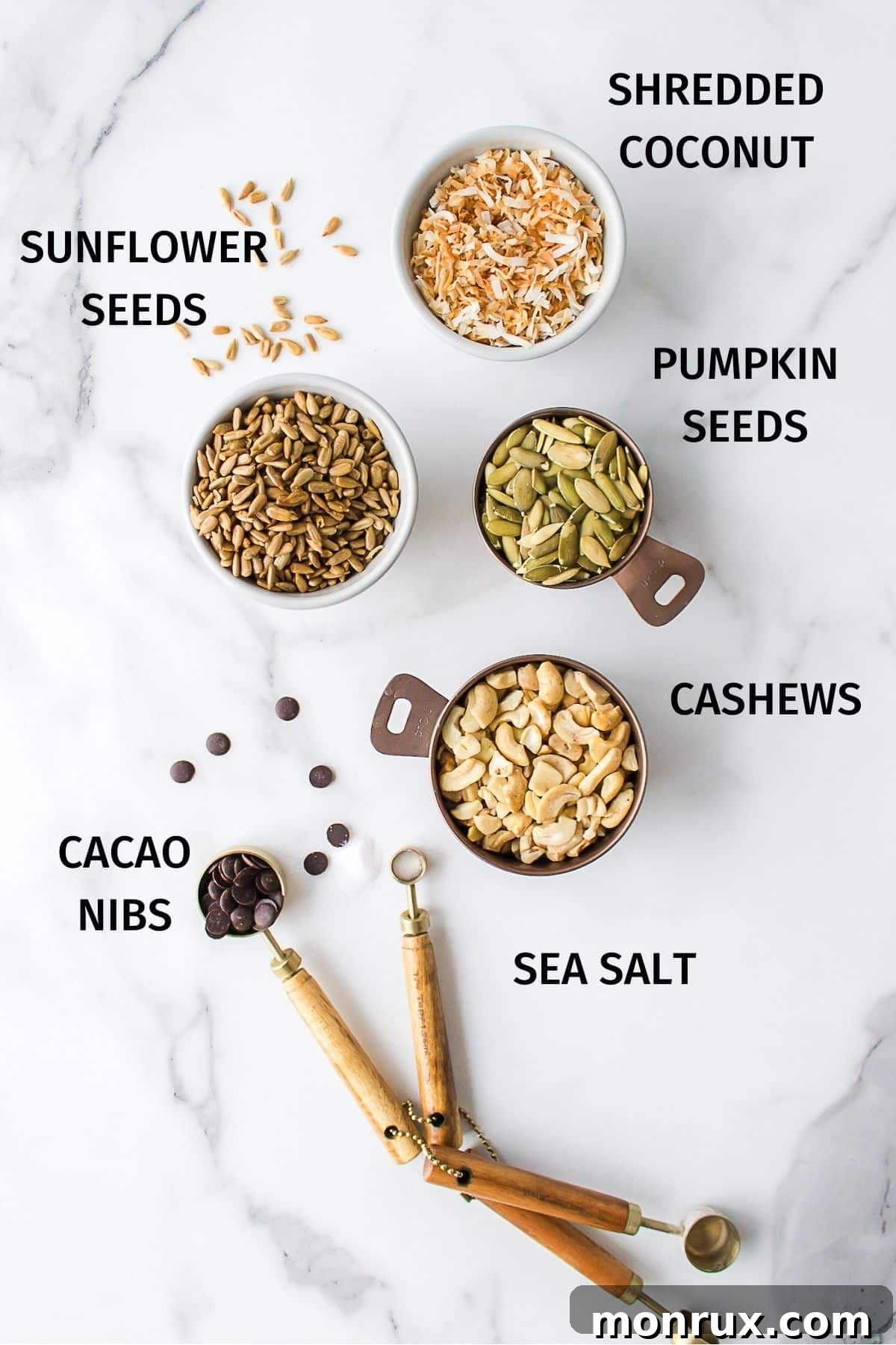 A close-up shot of the fresh ingredients for sugar-free trail mix, including cashews, pumpkin seeds, sunflower seeds, shredded coconut, and cacao nibs.