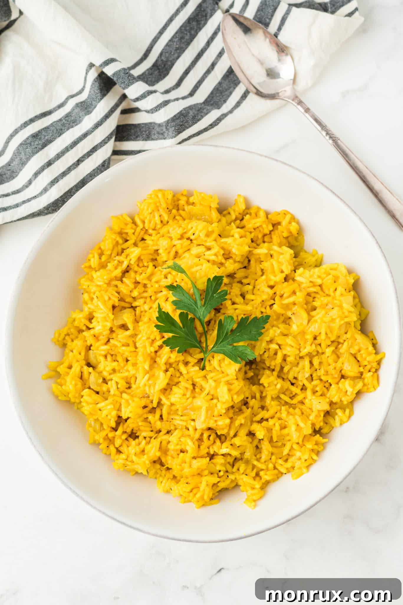 A close-up shot of a bowl of fluffy Instant Pot yellow rice, garnished with a fresh sprig of parsley, highlighting its vibrant color and inviting texture.