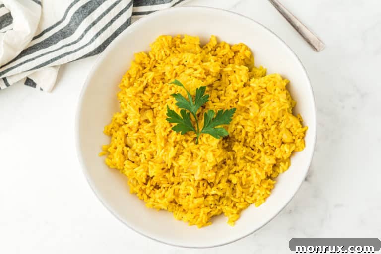 A bowl of vibrant yellow rice, garnished with fresh herbs.