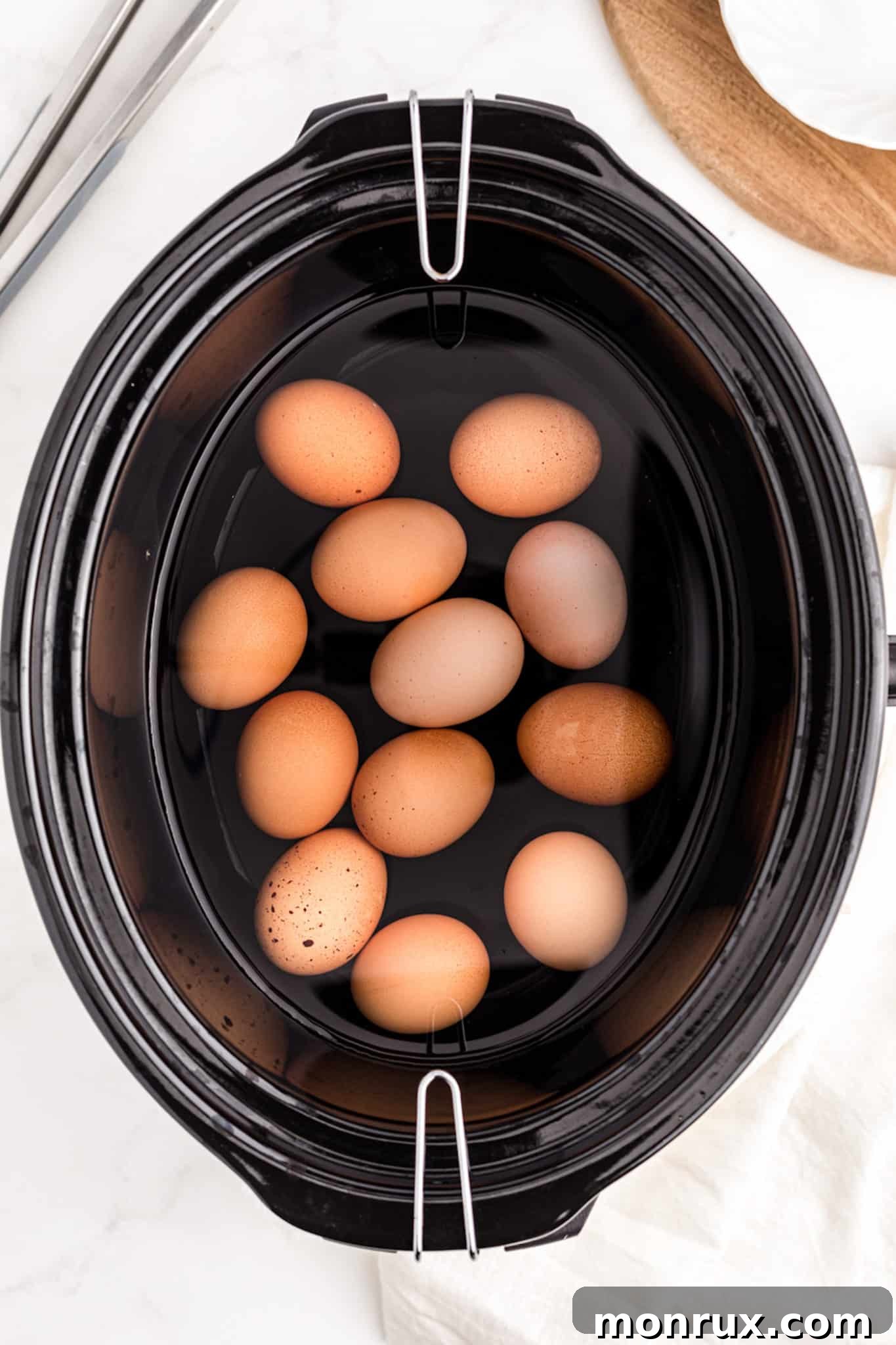 A slow cooker filled with eggs and water, ready for cooking.