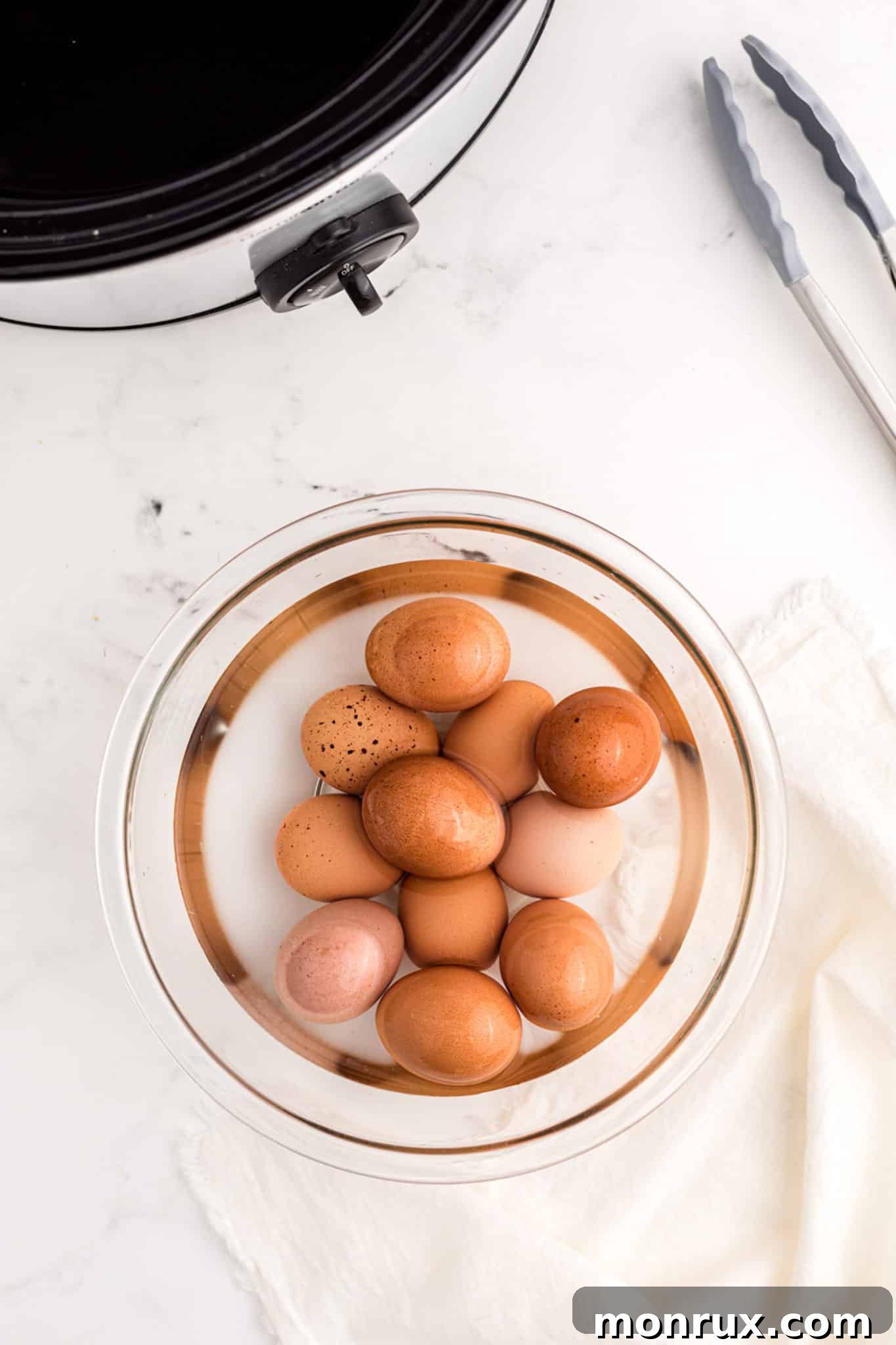 Boiled eggs cooling in water after being cooked in a slow cooker.