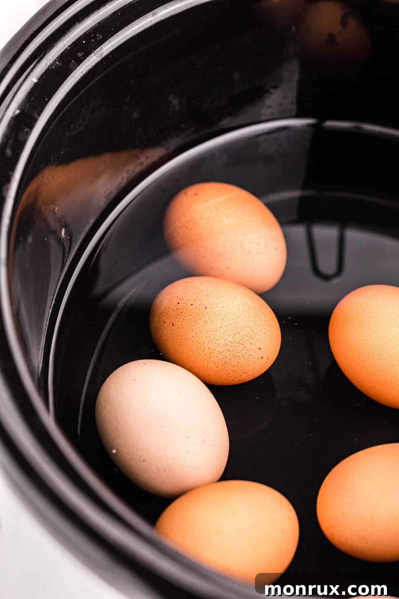Eggs neatly arranged inside a slow cooker before cooking.