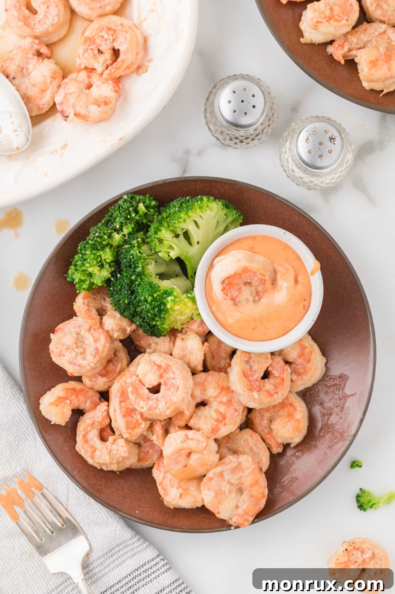 A close-up of a plate featuring perfectly cooked shrimp and fresh broccoli, ready to be enjoyed.