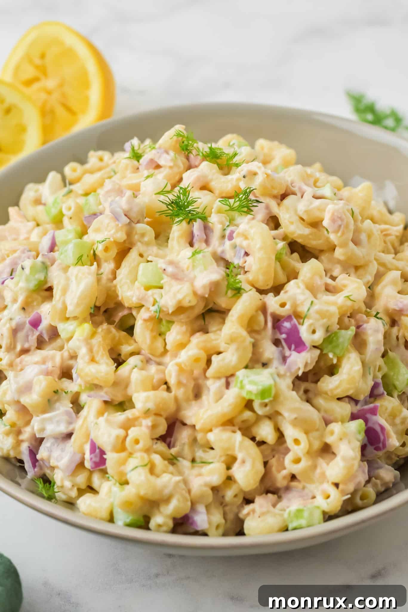A vibrant bowl of gluten-free tuna pasta salad, garnished with fresh herbs, ready to be served.