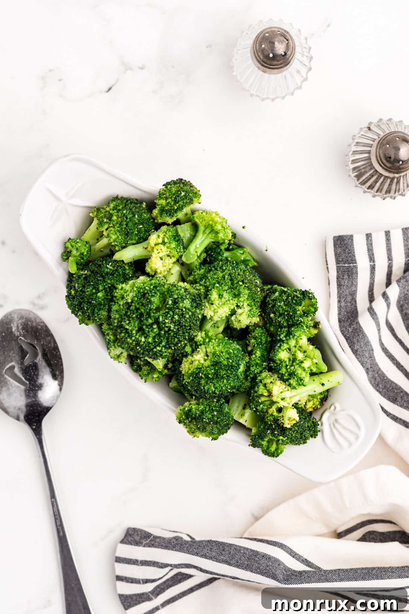 A white serving tray filled with vibrant green steamed broccoli florets.