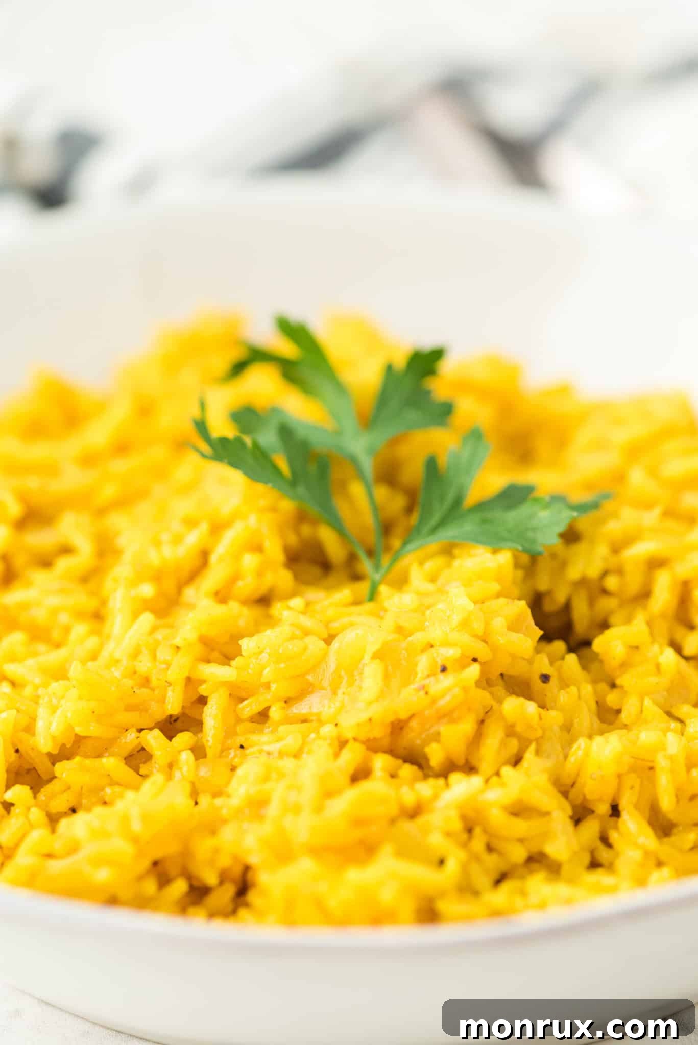 A simple white bowl generously filled with fluffy, cooked yellow rice.