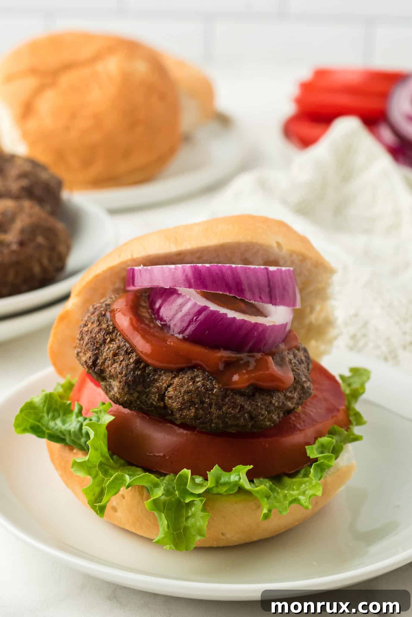 A juicy hamburger on a bun, topped with a thick slice of red onion.