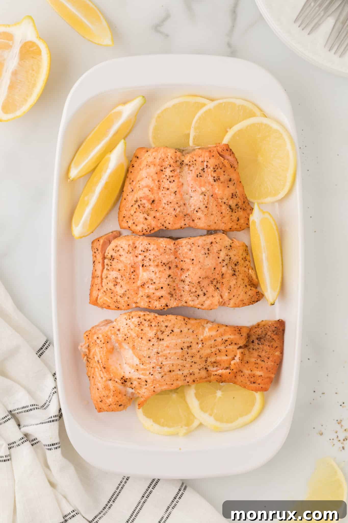 A elegant platter featuring baked salmon fillets garnished with fresh lemon slices and herbs.