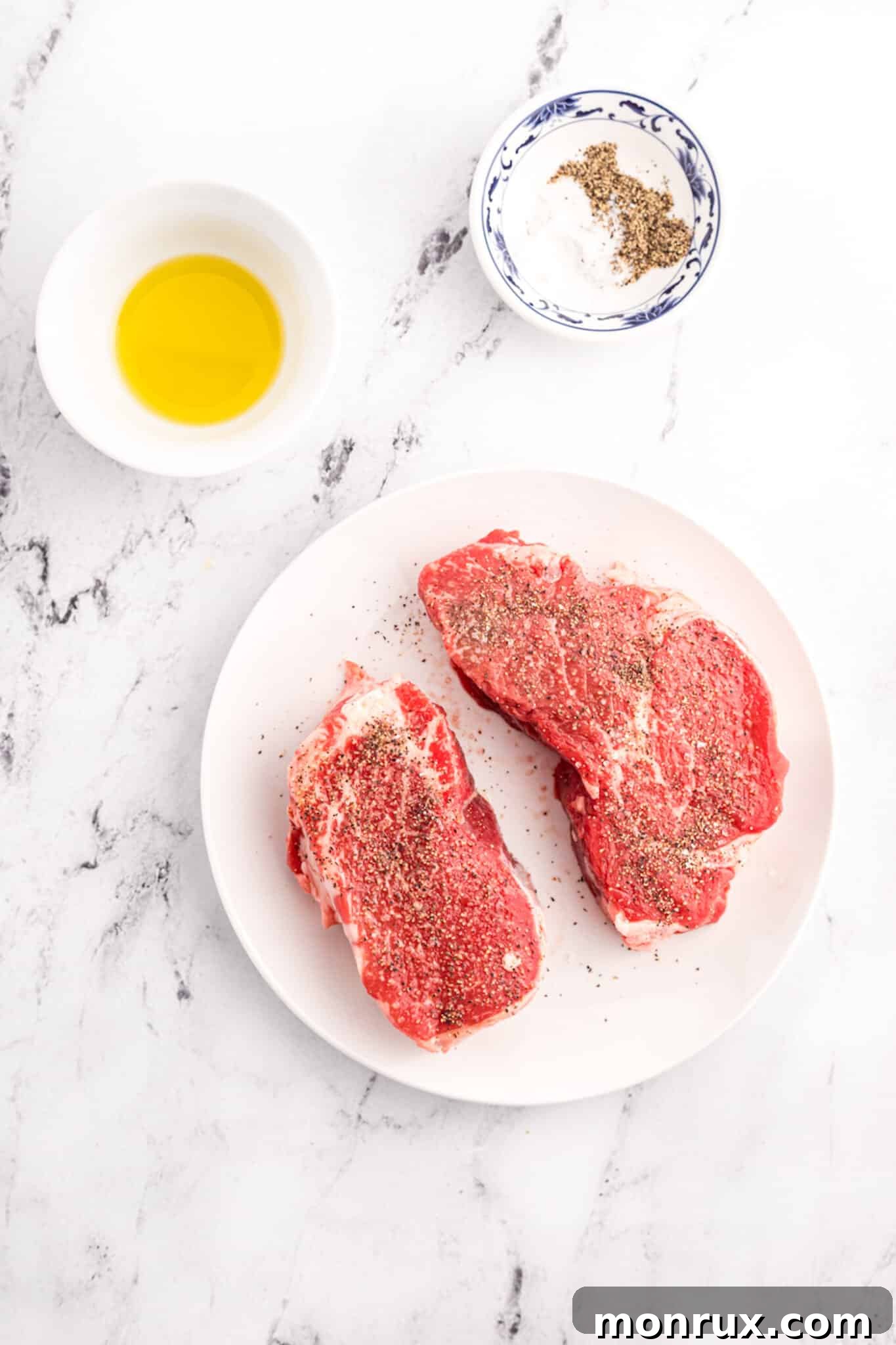 Filet mignon steaks sitting on a plate at room temperature, ready for seasoning.