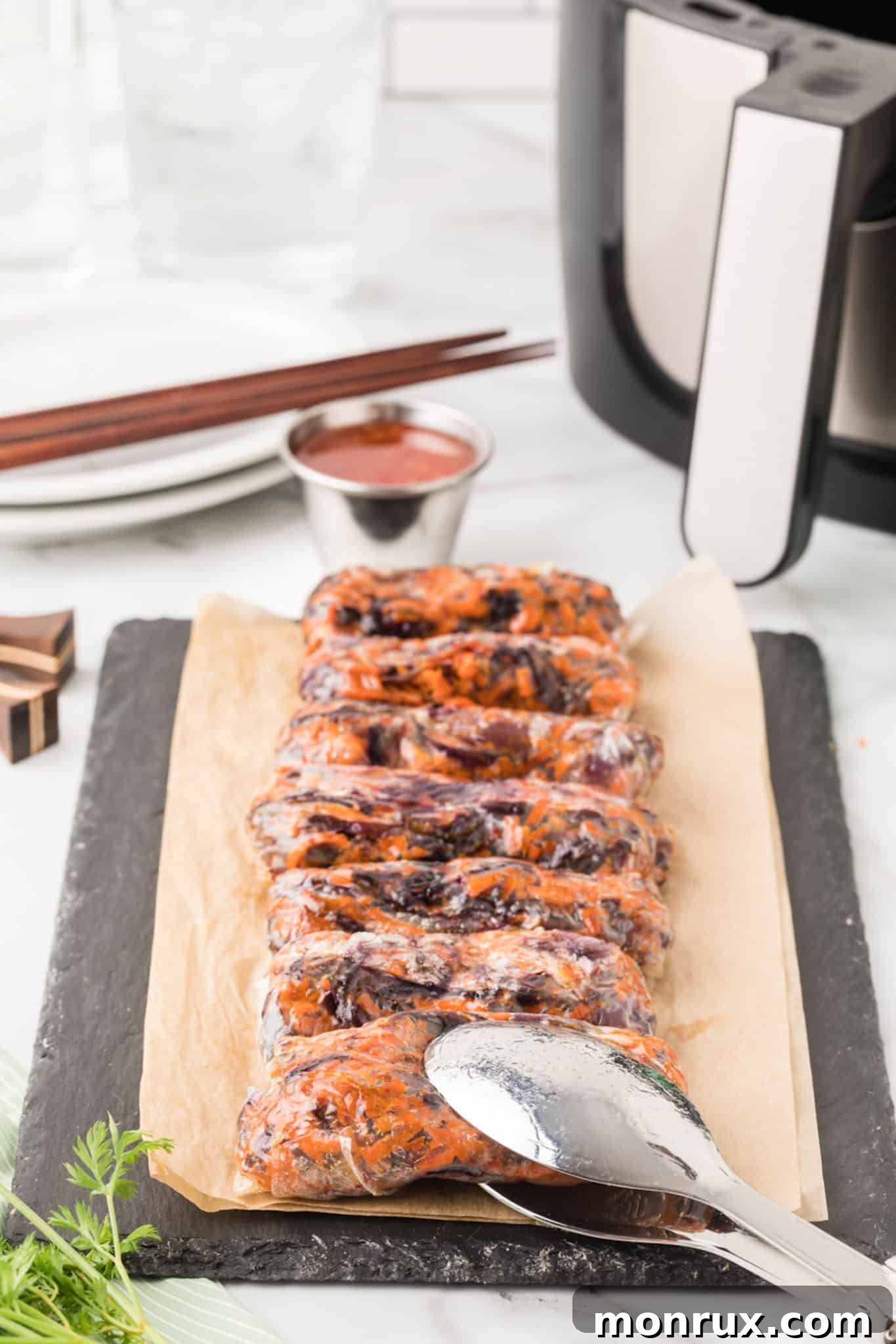 Crispy Air Fryer Spring Rolls on a platter with chopsticks and a bowl of dipping sauce, highlighting their golden-brown perfection.