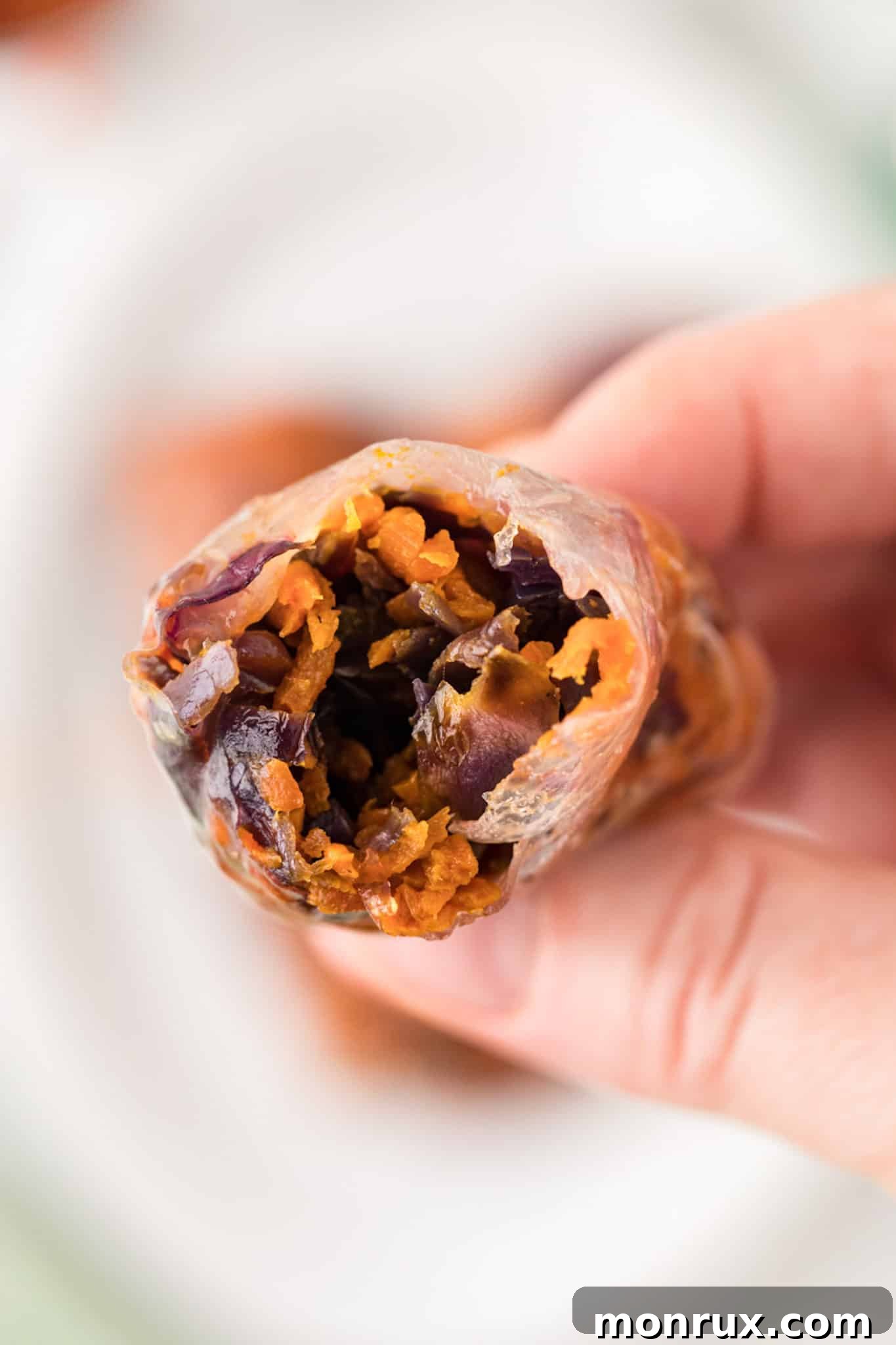 A perfectly air-fried spring roll with a bite taken out, showcasing its crispy exterior and vibrant vegetable filling.