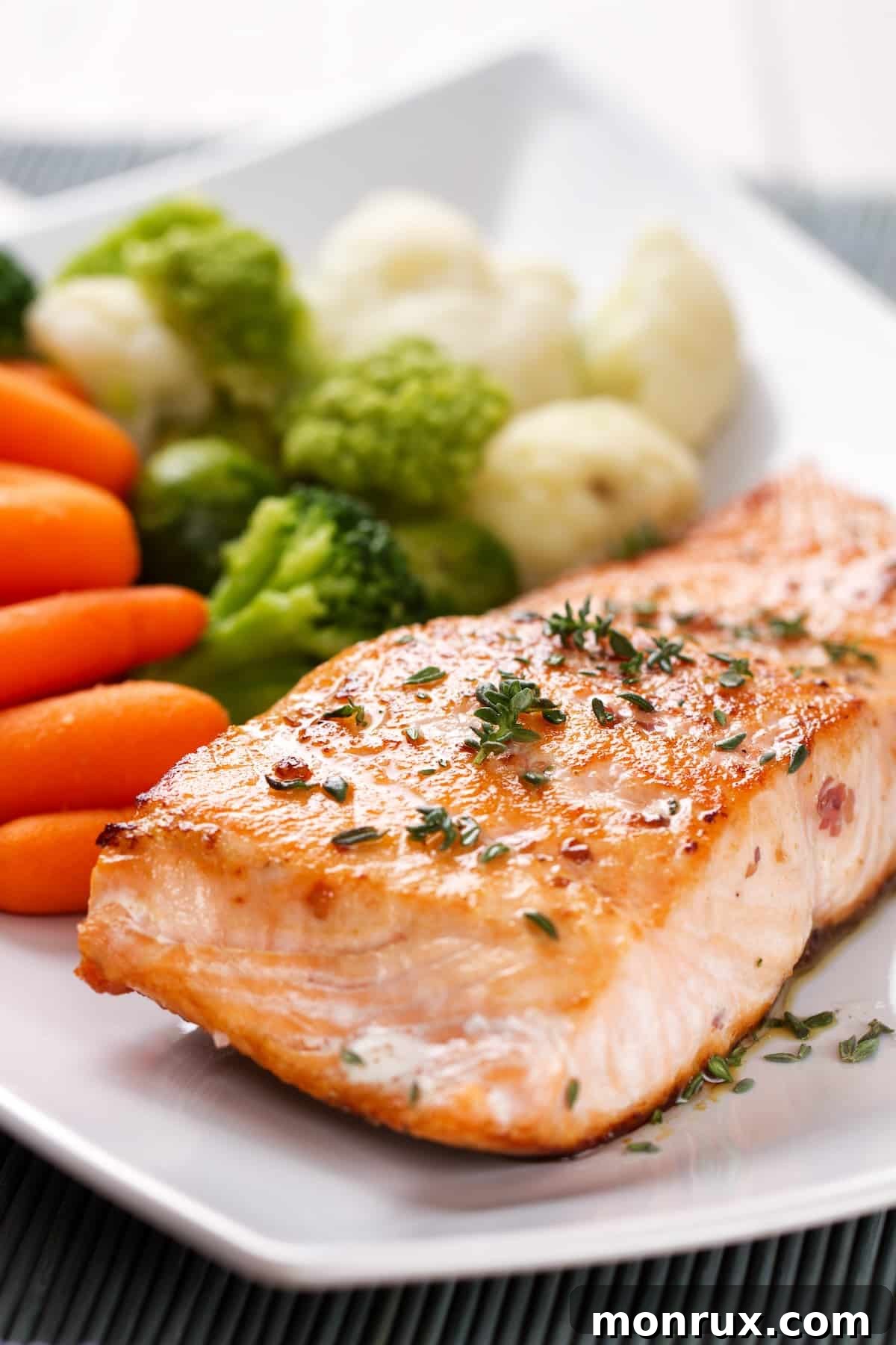 air fryer frozen salmon served on plate with vibrant green veggies.