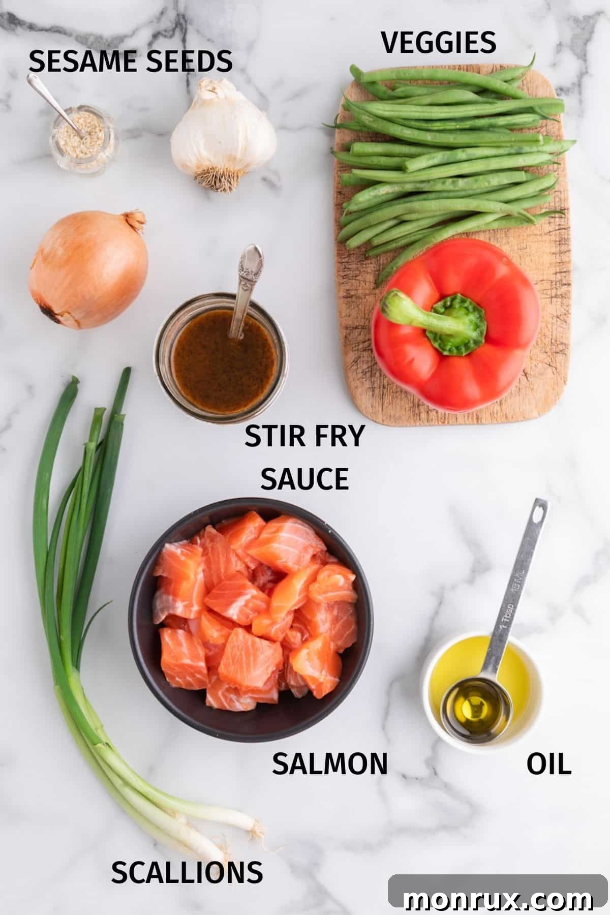All the fresh ingredients for salmon stir fry, including raw salmon, various vegetables, and sauce, neatly arranged on a white marble surface.