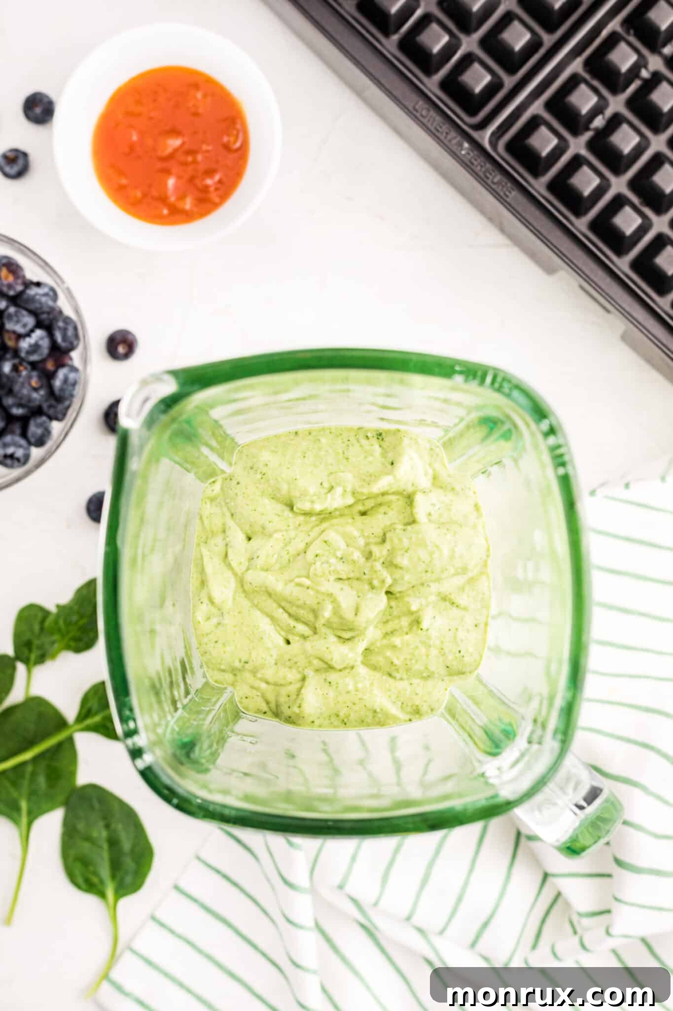 The blended green waffle batter, smooth and vibrant in a blender jar.