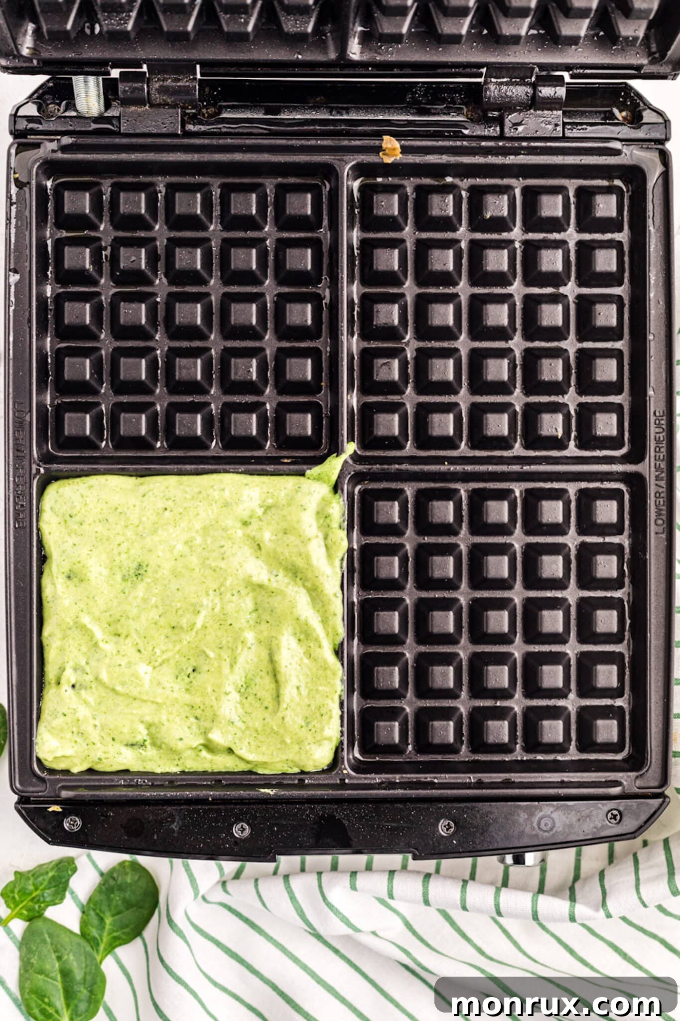 Pouring the green waffle batter directly onto a preheated waffle iron.